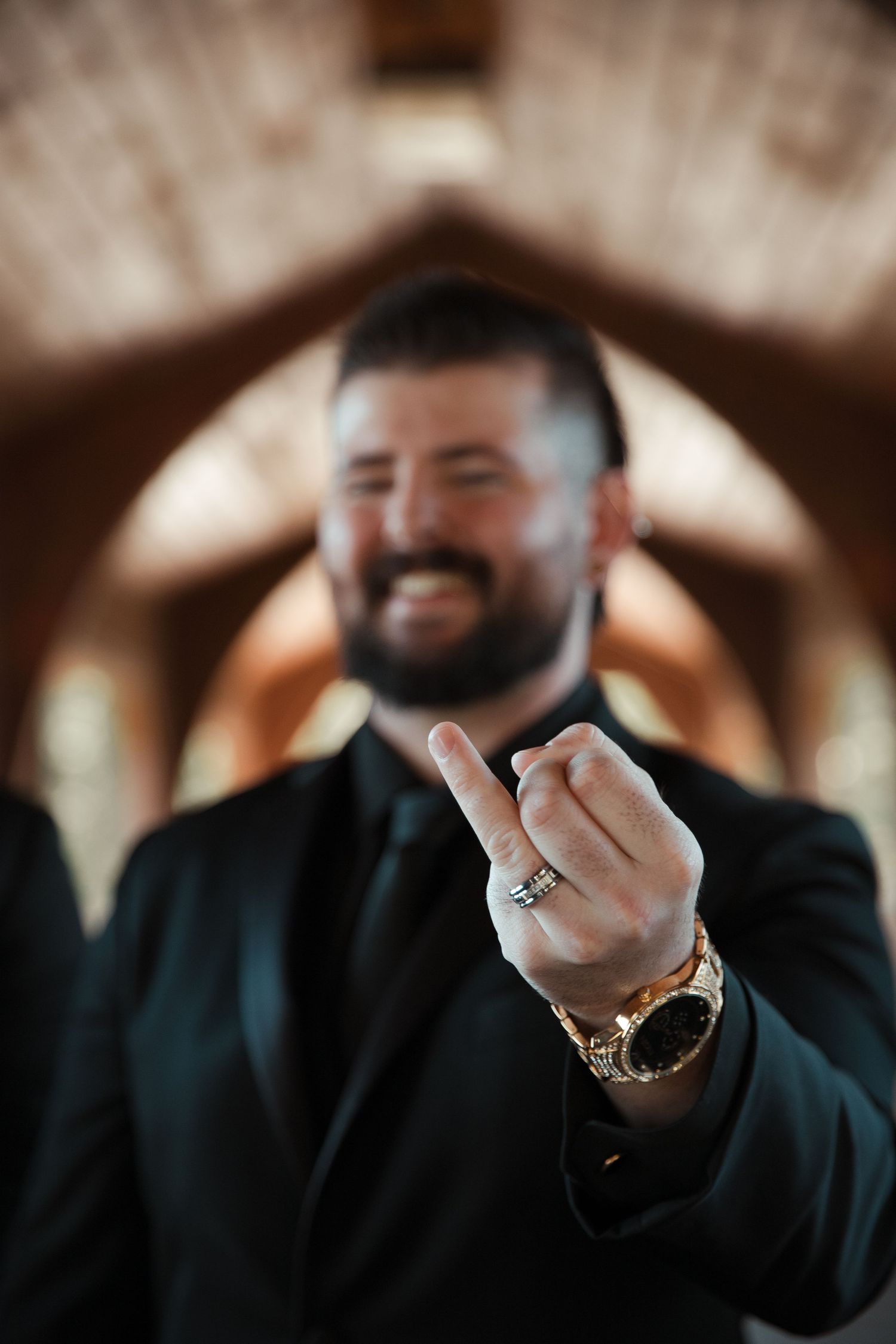 A close-up shot of a groom showing off his wedding ring with a joyful smile. wedding