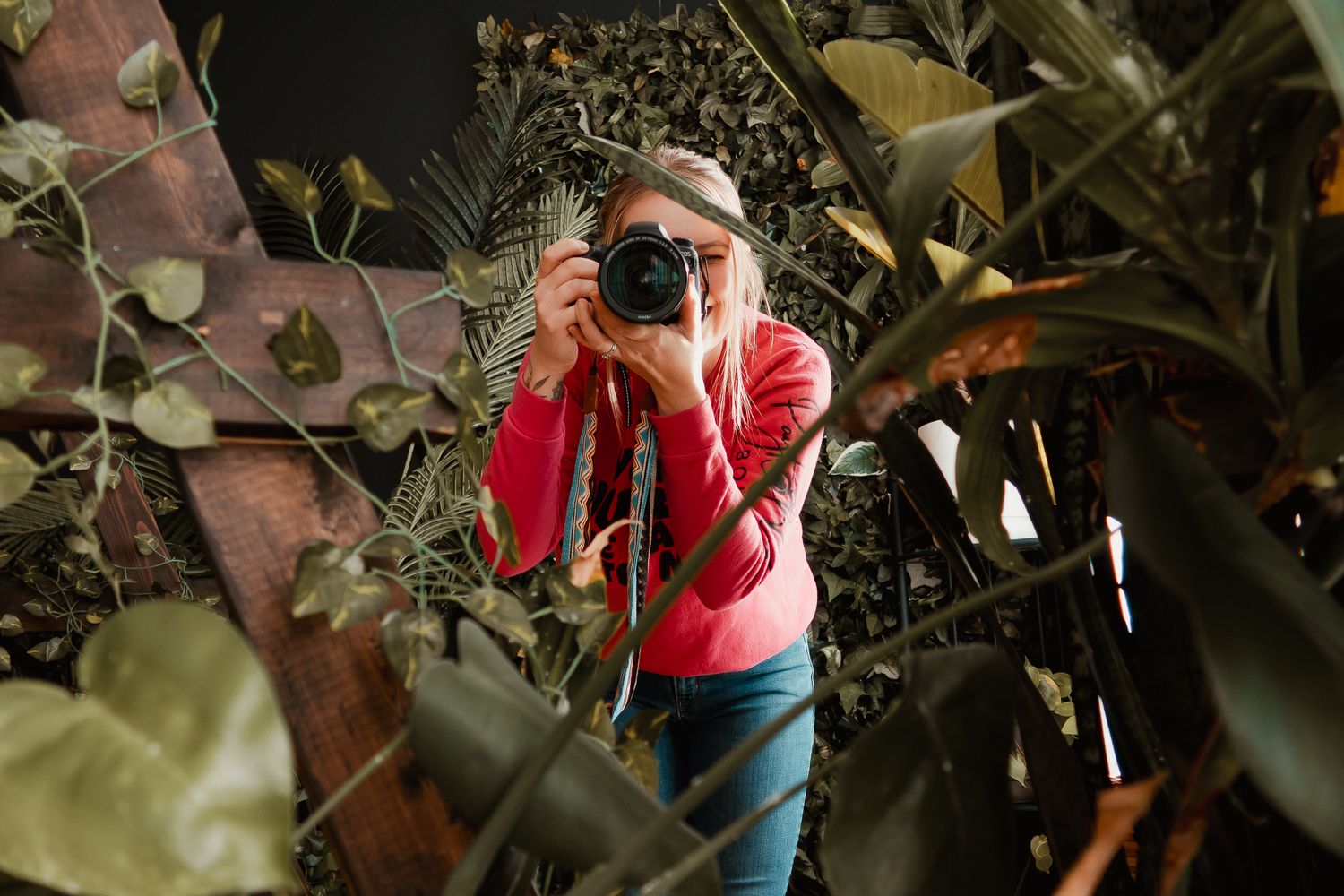 Photographer in red jacket capturing images among green foliage. me photographer selfie