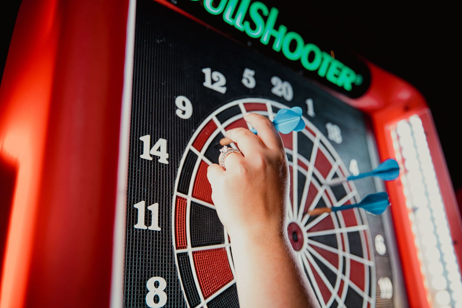 Close-up of a hand reaching for a dart board with neon lighting. wedding