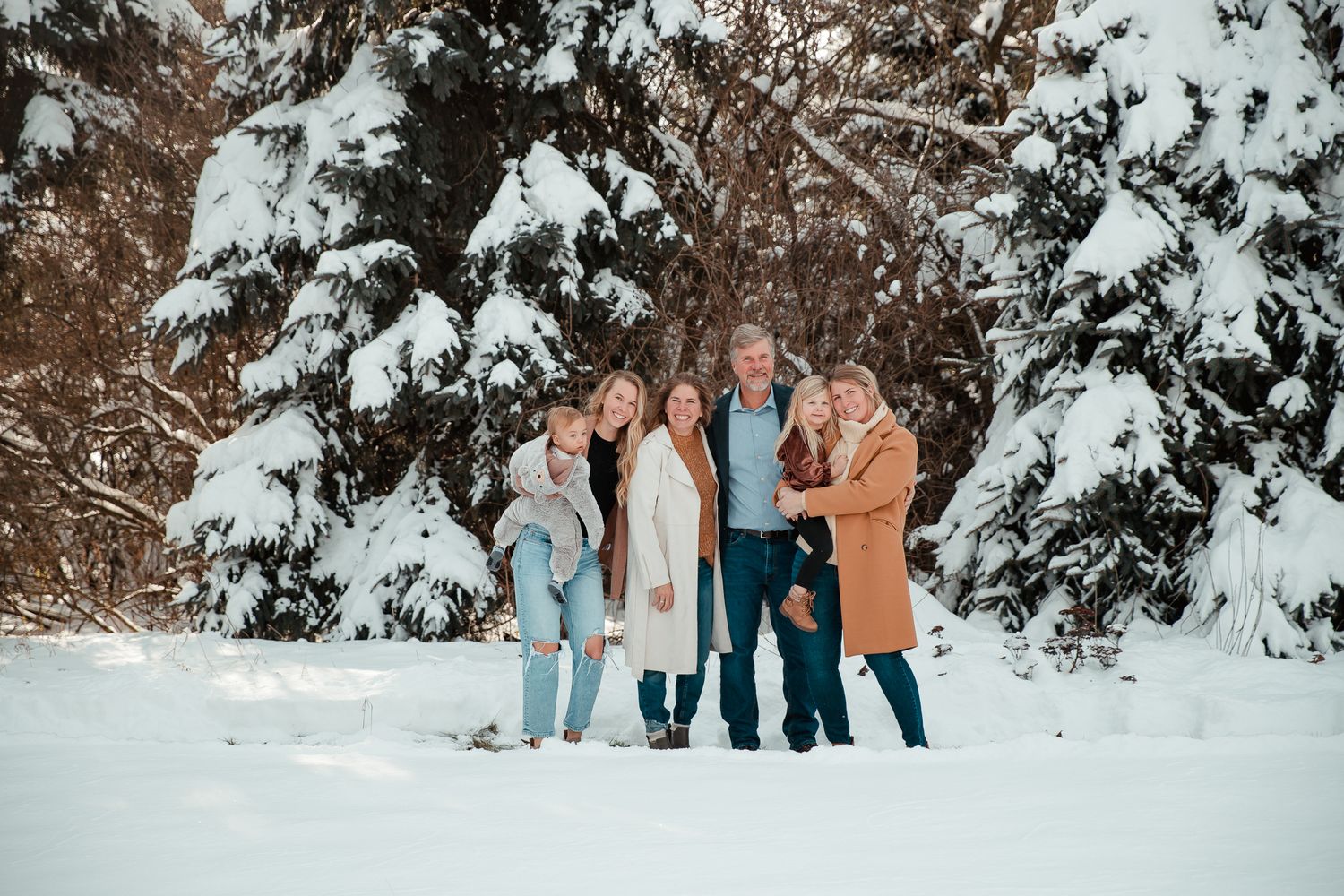 A group enjoying a winter day together against a snowy evergreen forest backdrop.