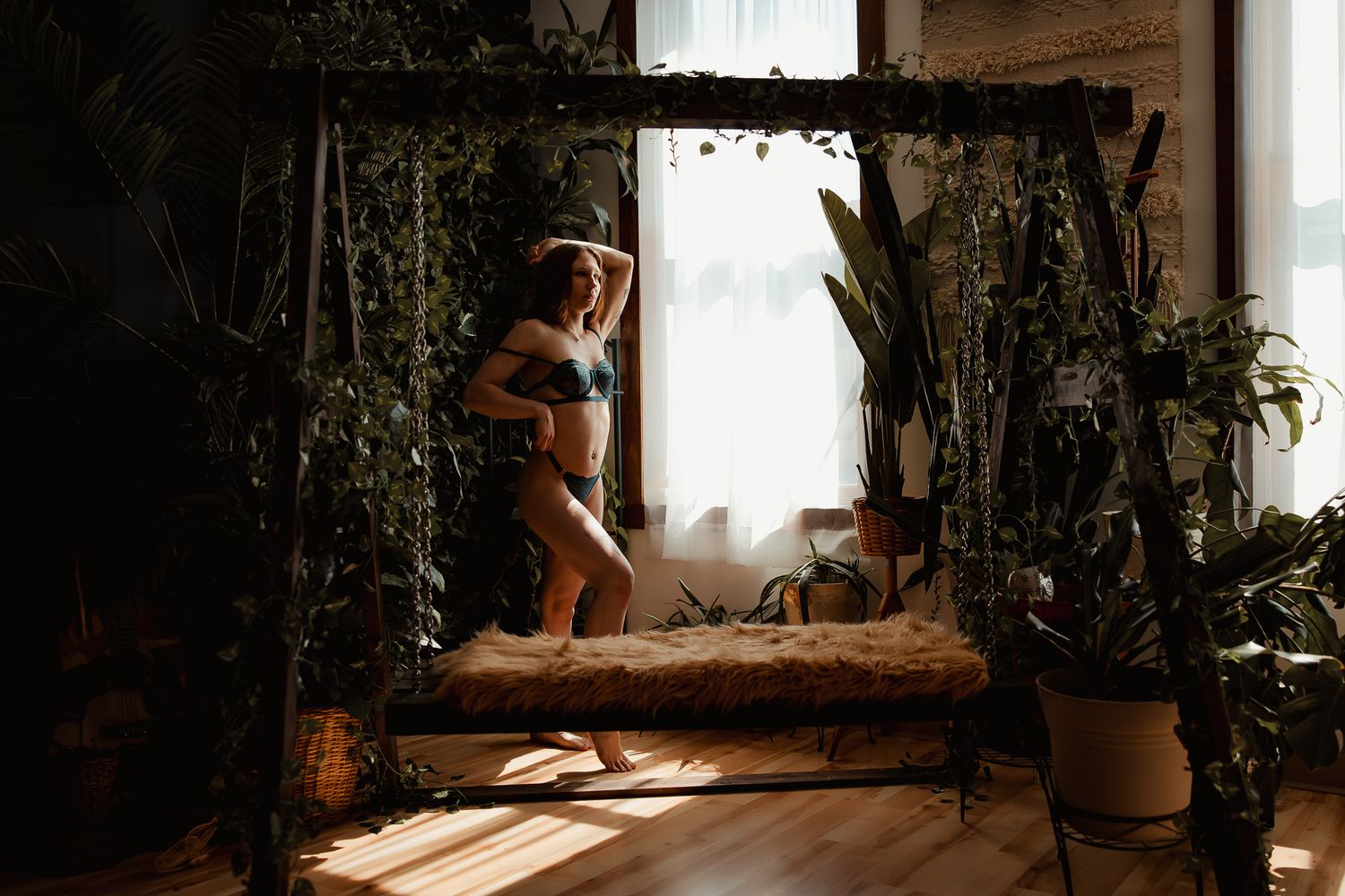 Beautiful indoor sunlit space with greenery, vines, and a vintage wooden canopy bed by a large window.