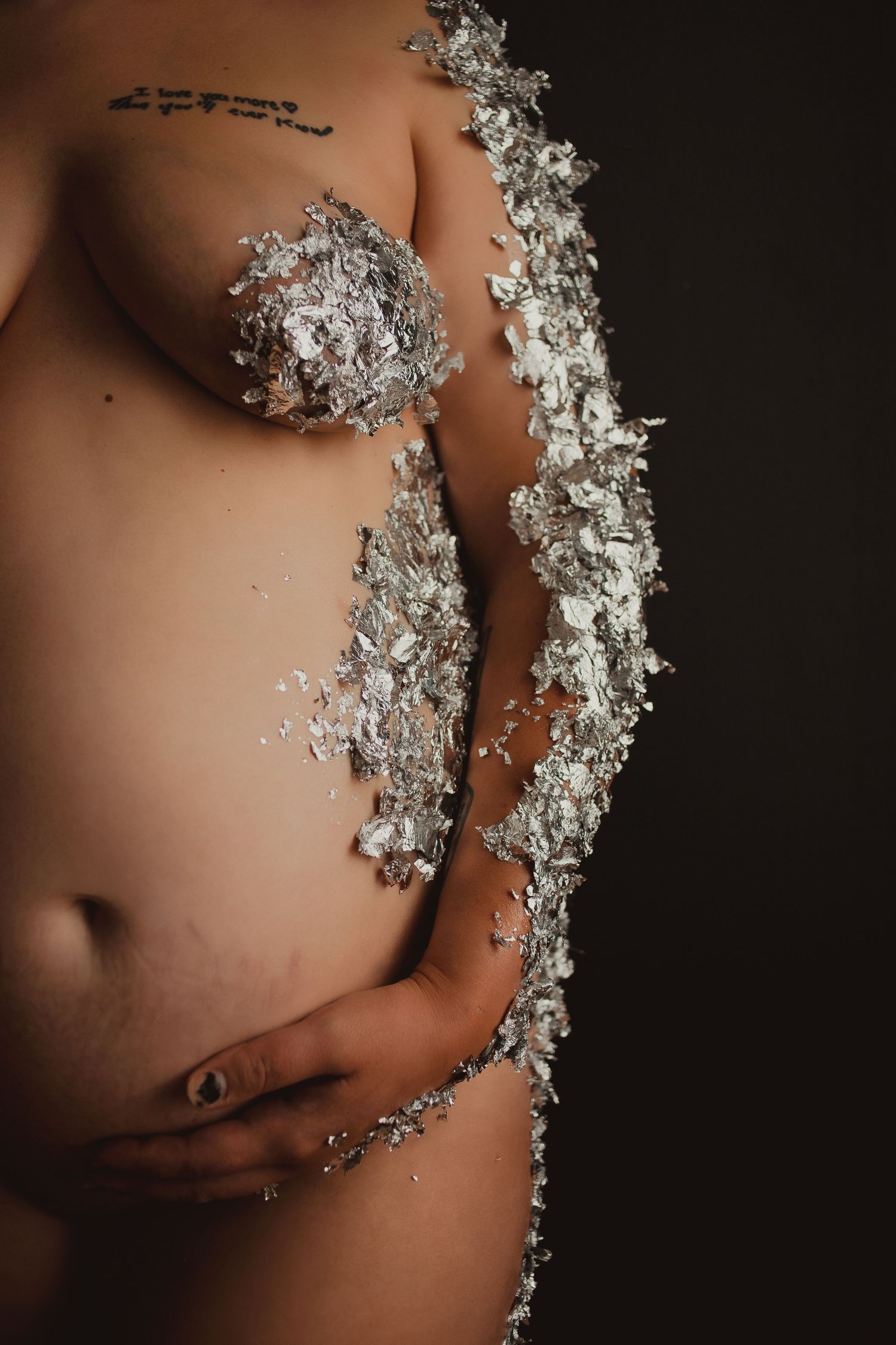 Artistic nude torso covered in a diagonal line of crushed ice or glass crystals against dark background.