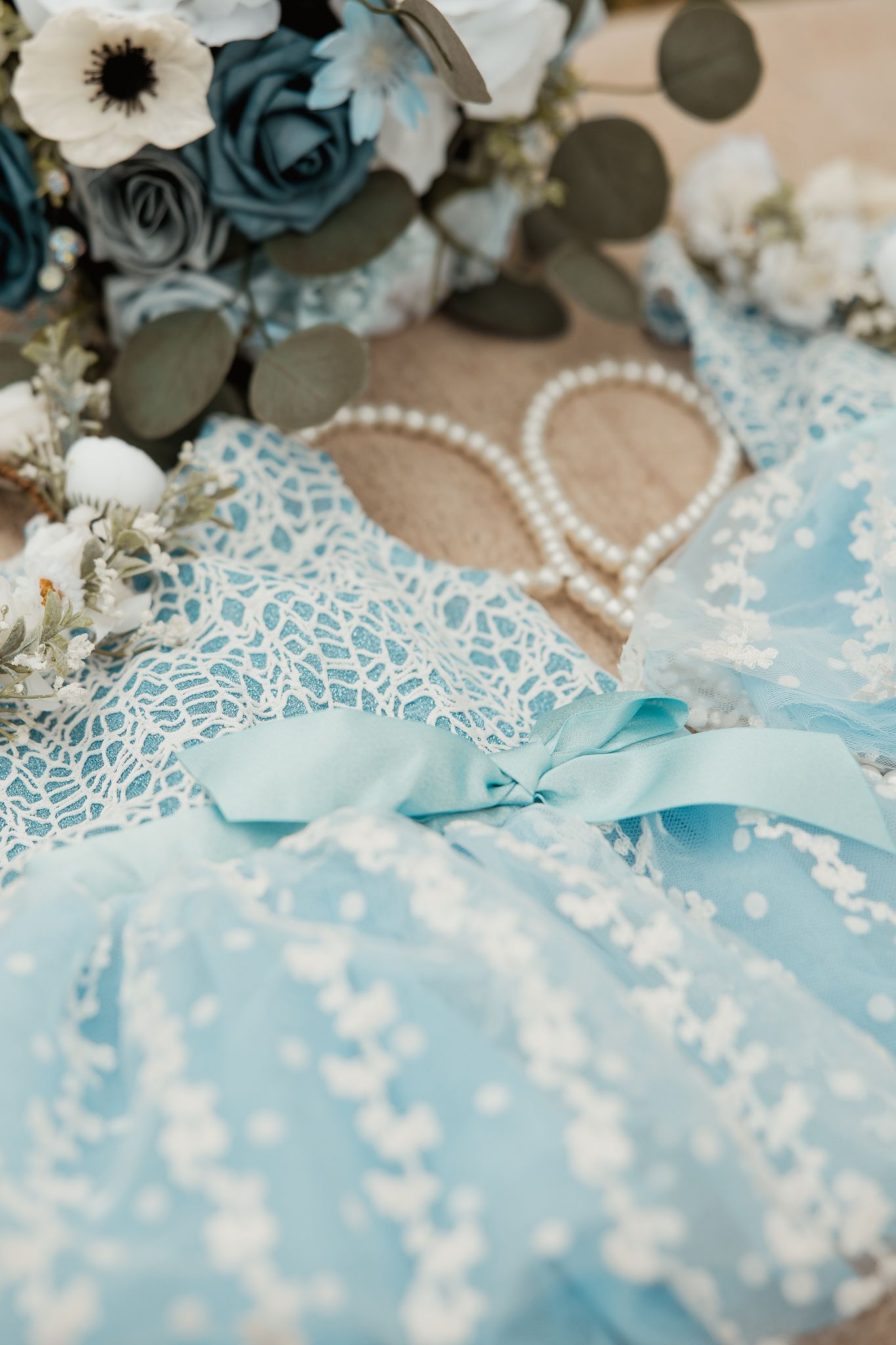Delicate teal lace and pearl decorations create an elegant wedding backdrop with dark blue floral accents.