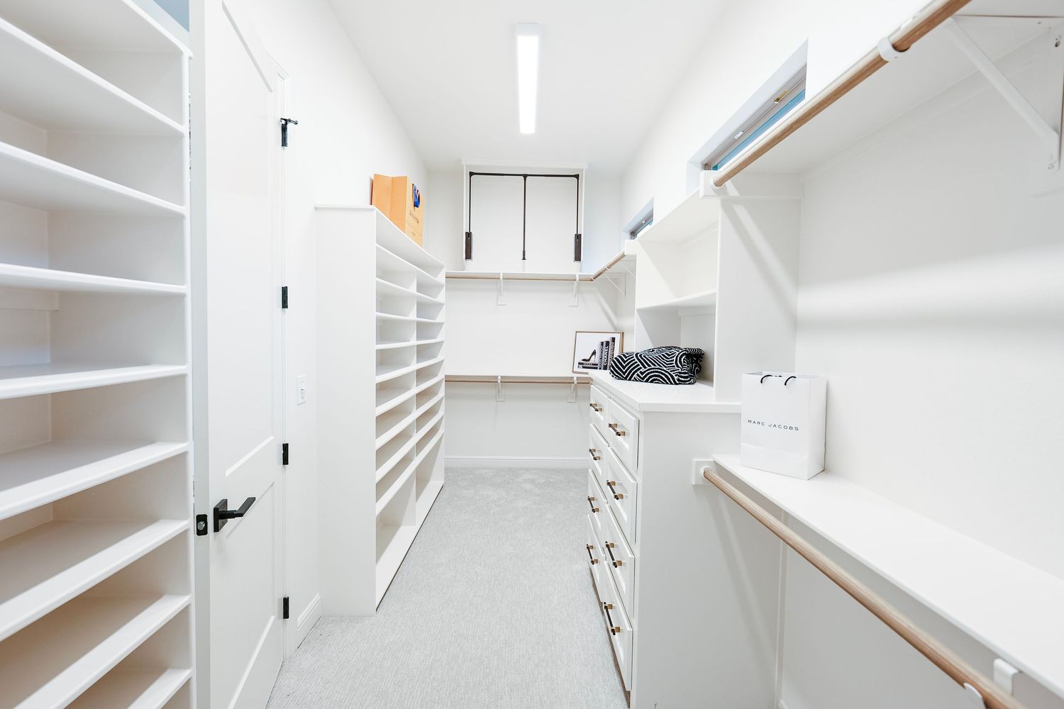 Bright white walk-in closet with built-in shelving and storage solutions.