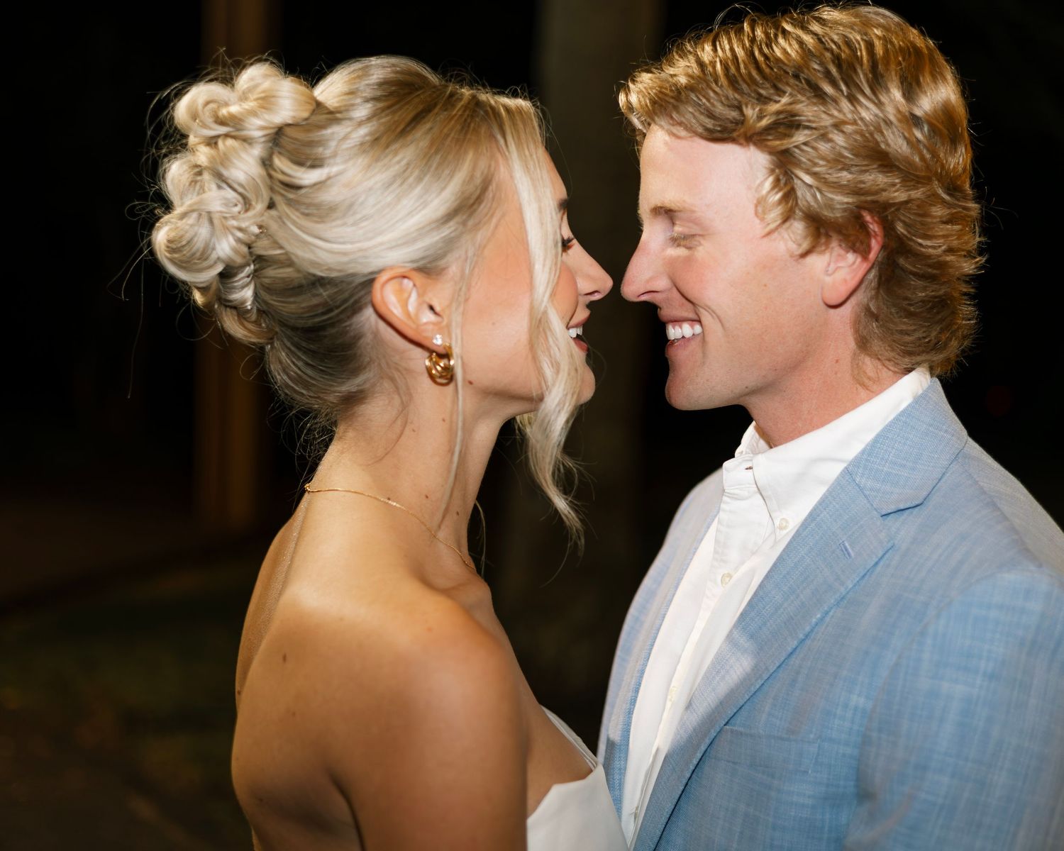 Romantic couple shares intimate moment on dance floor with twinkling lights in background.