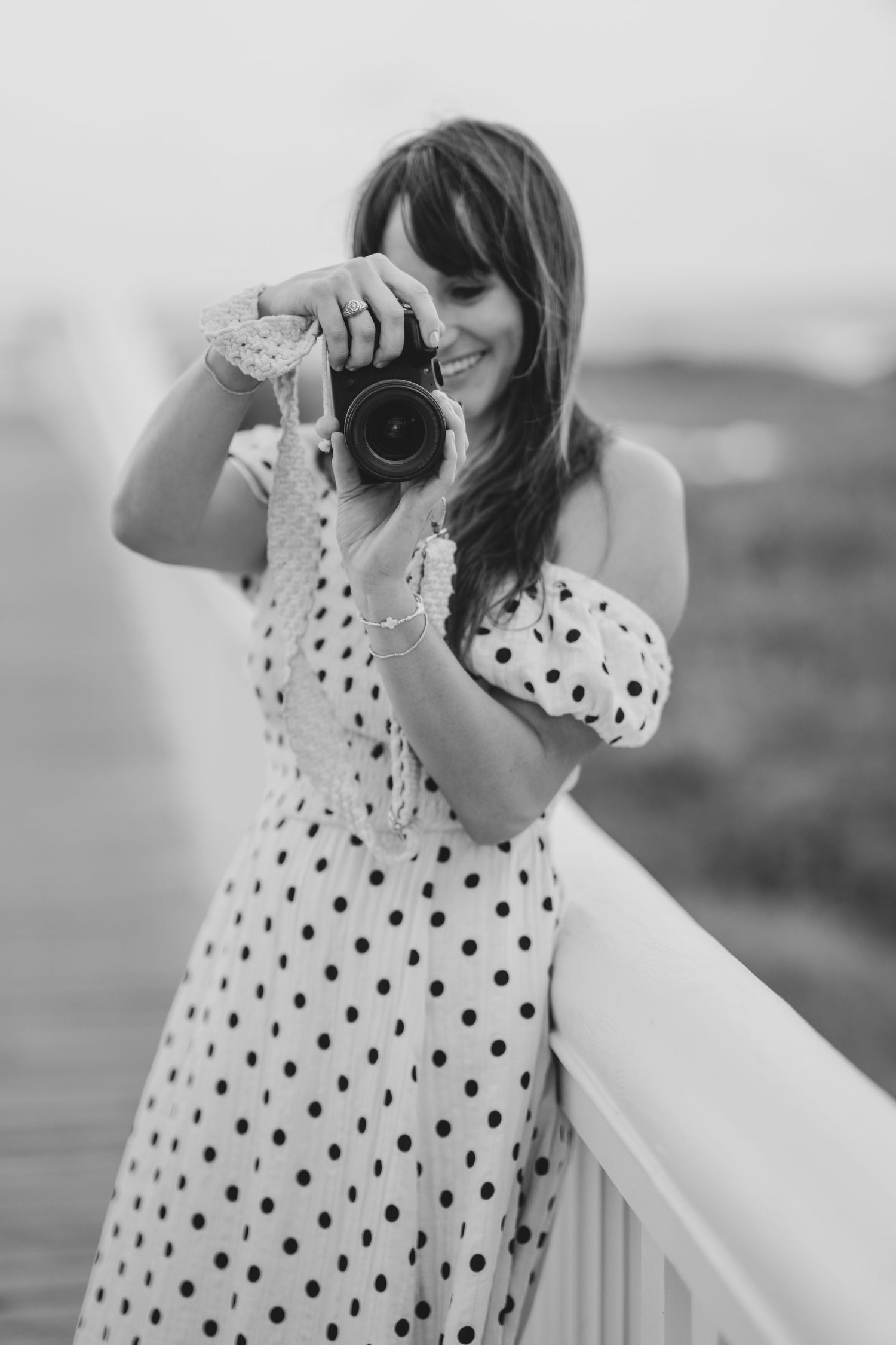 Black and white series showing someone in a polka dot dress taking photos on a balcony.