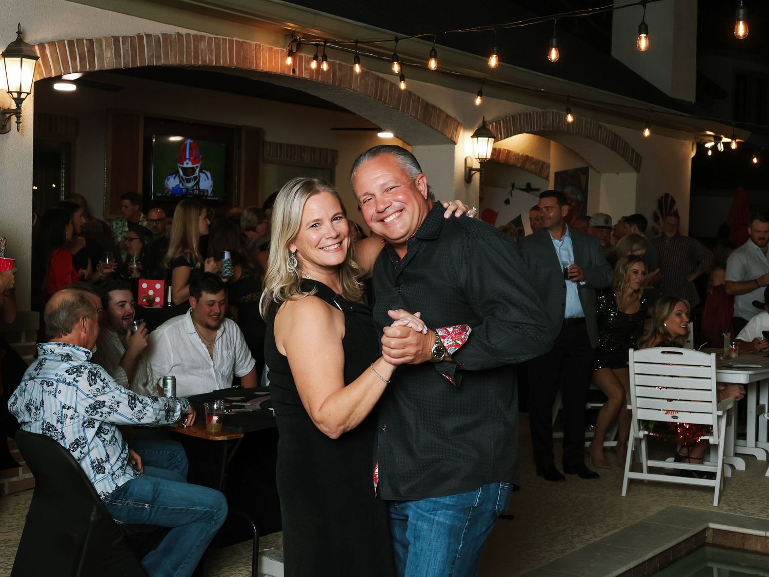 Couples dance together at a social gathering with pendant lights hanging from the ceiling.