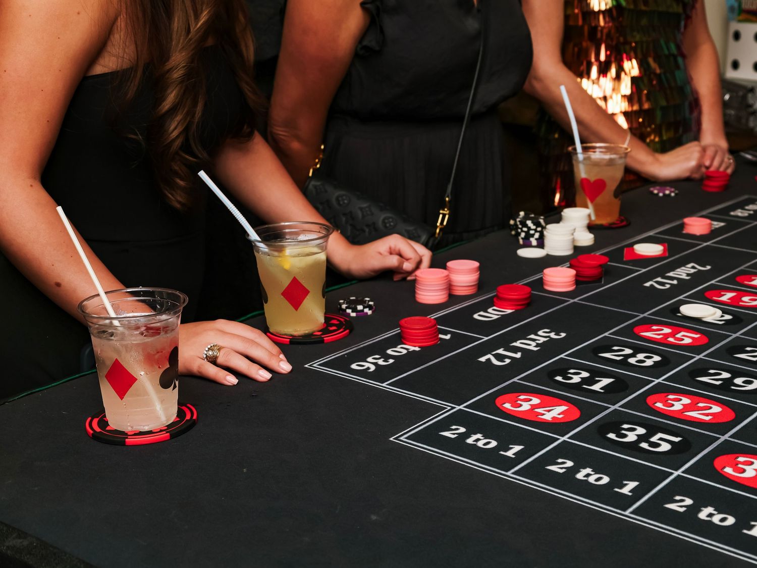 Close-up view of players placing bets on a casino roulette table with red and black numbered squares.