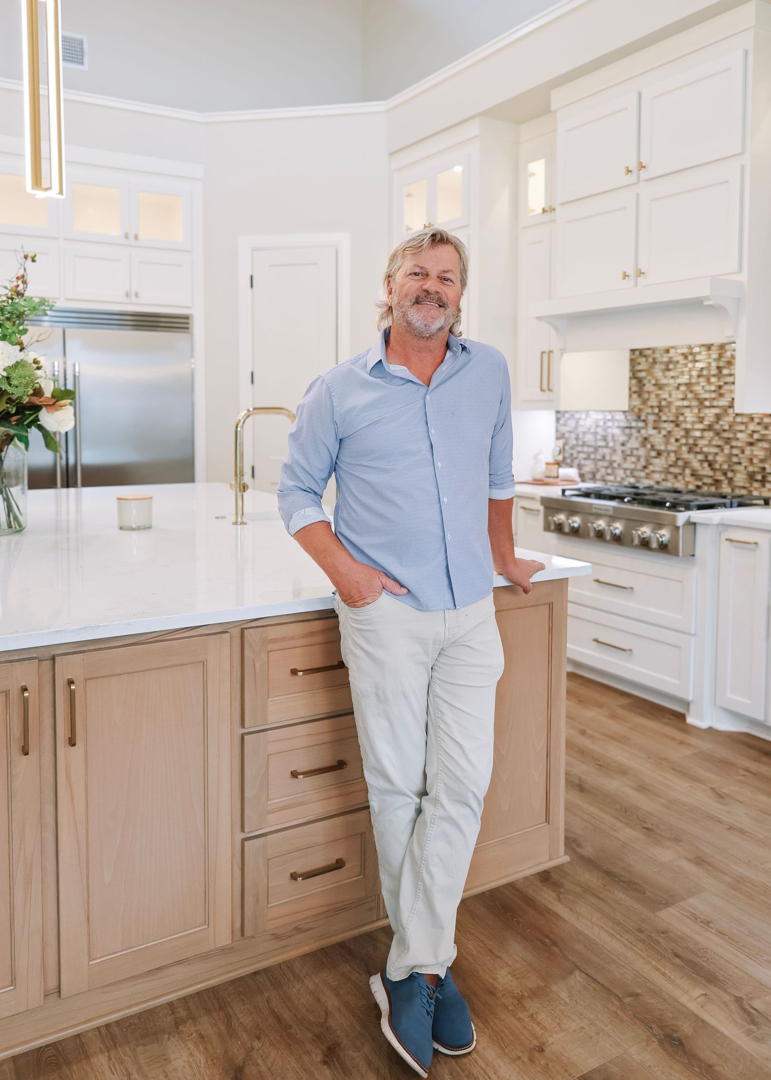 Professional real estate agent standing in modern white kitchen with hardwood floors.