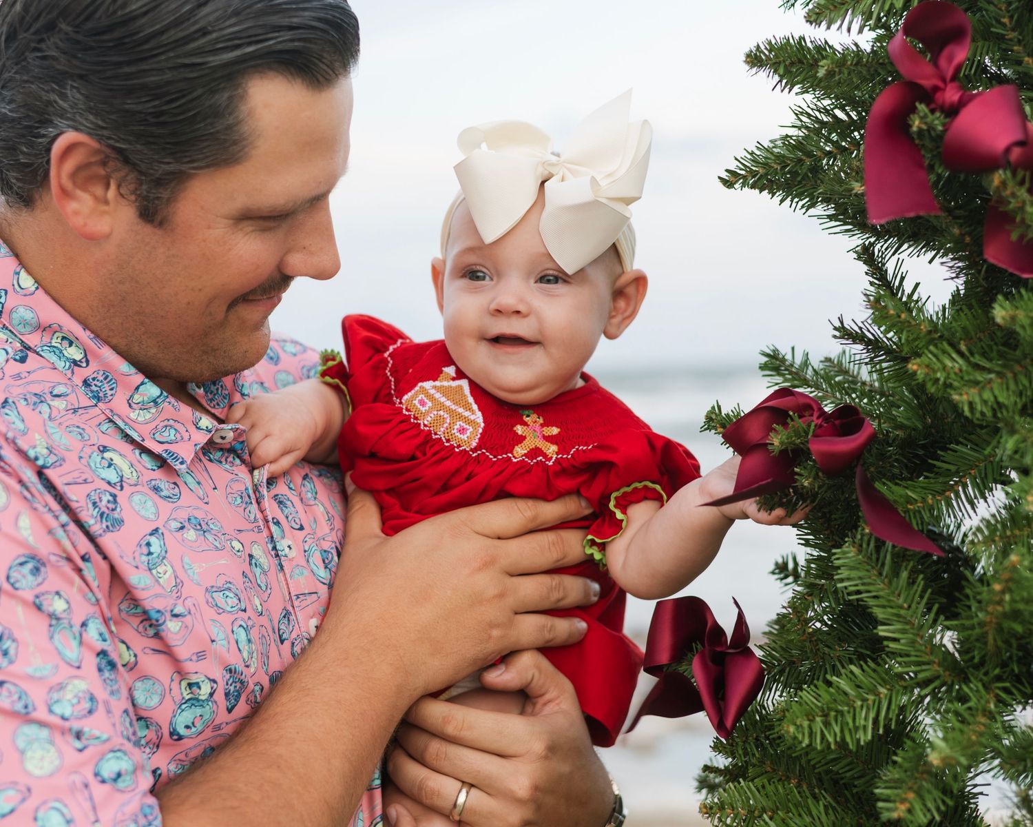 A series of holiday photos showing tender moments by a Christmas tree with red decorations and bows.