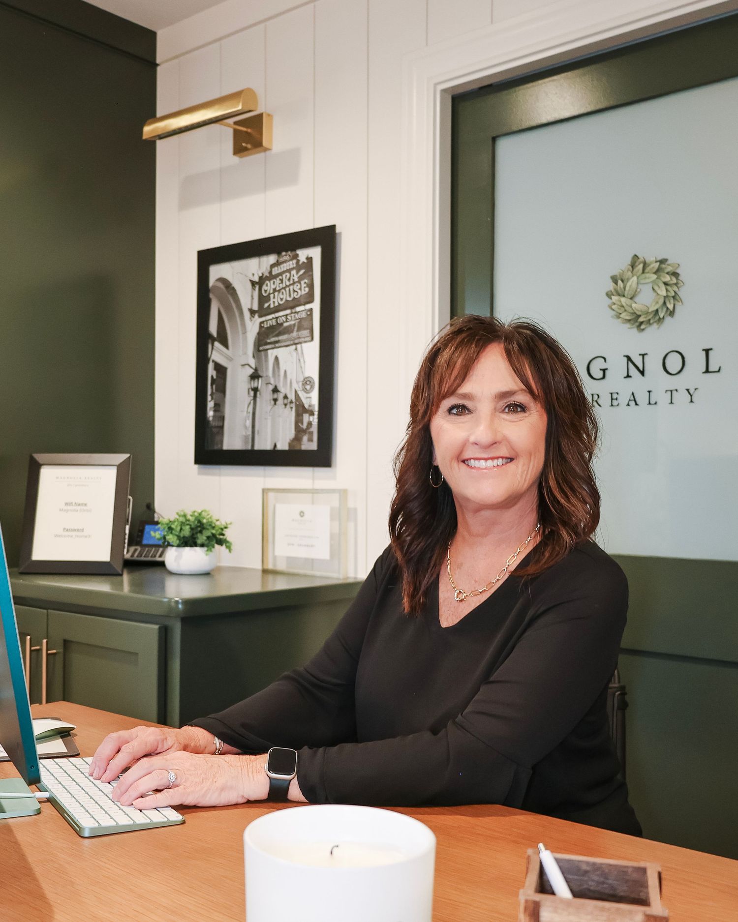 Real estate agent working at desk in modern office with Magnolia Realty branding.