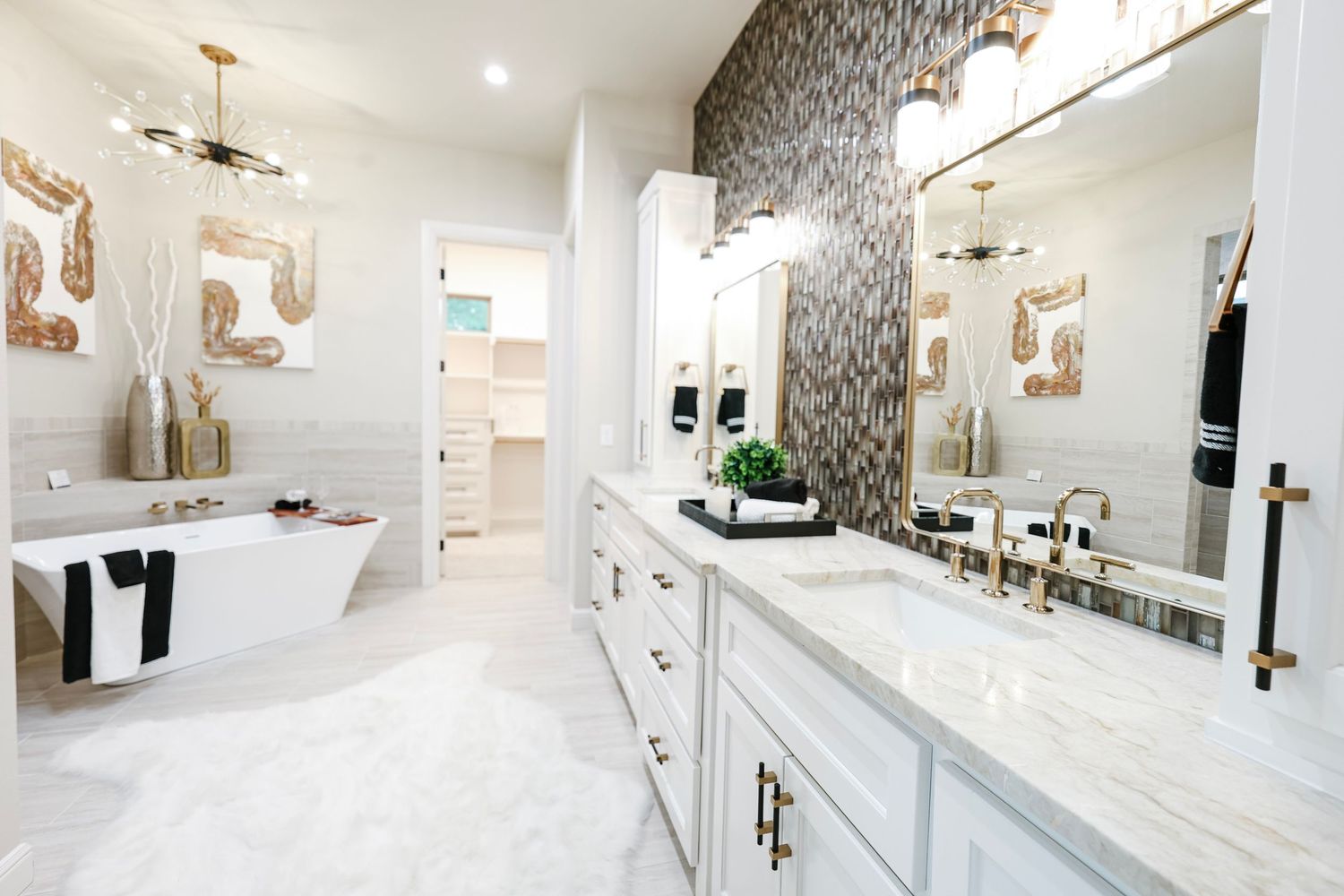 Elegant white kitchen with marble countertops and decorative wallpaper accent wall.