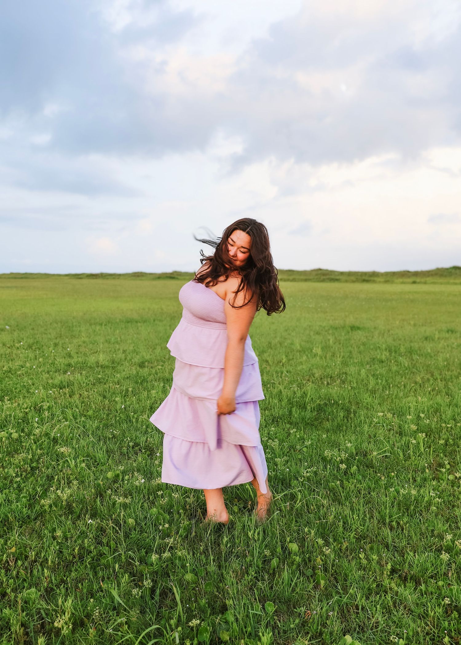 Carefree moments of dancing and spinning in a lavender dress amid green fields.