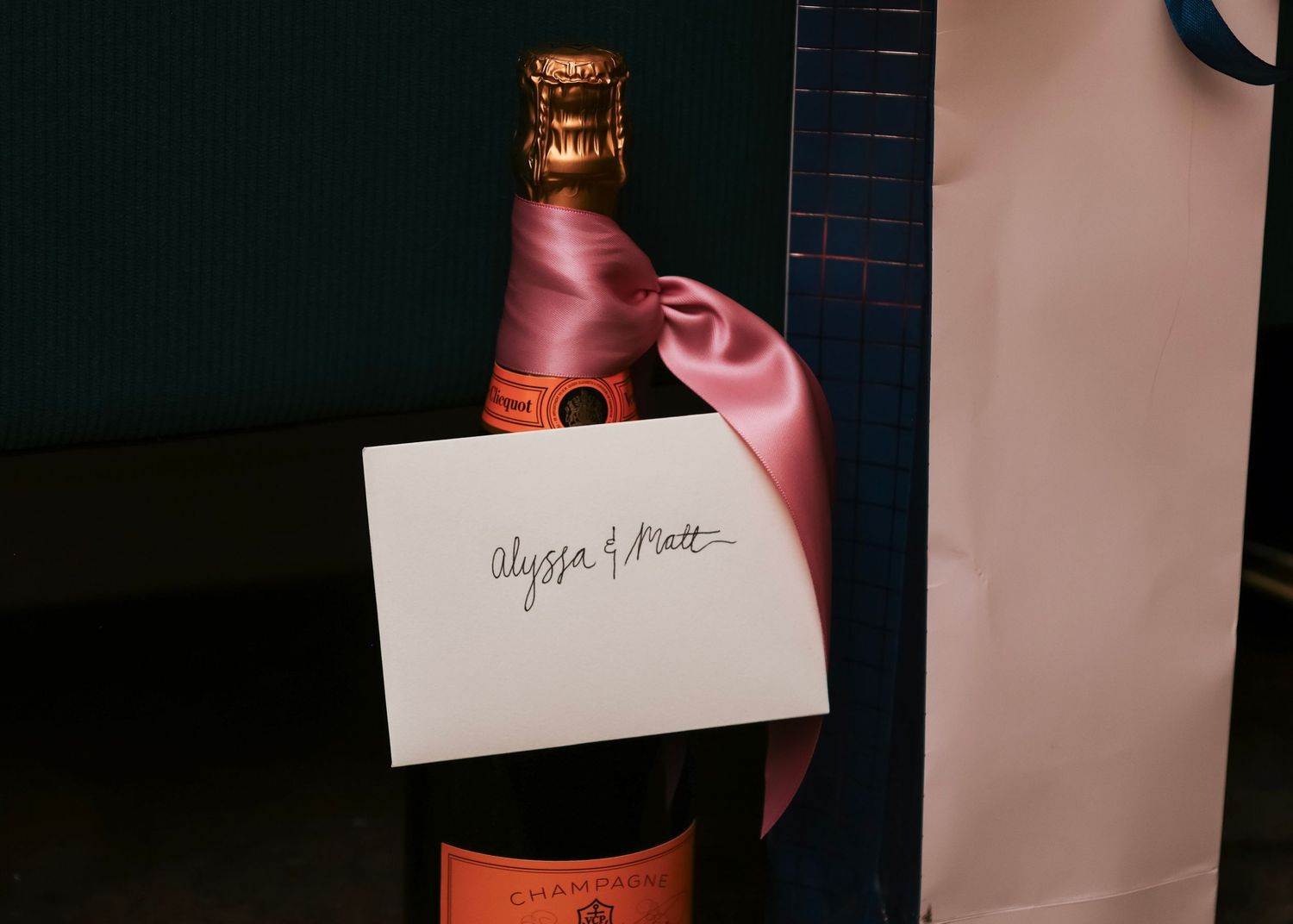 Close-up of champagne bottles and place cards arranged on a dark surface with soft lighting.