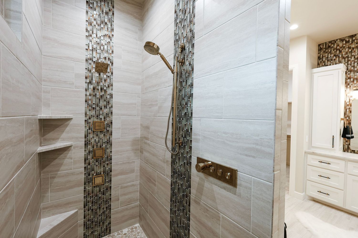 Elegant bathroom featuring mosaic tile accent wall and white cabinetry.