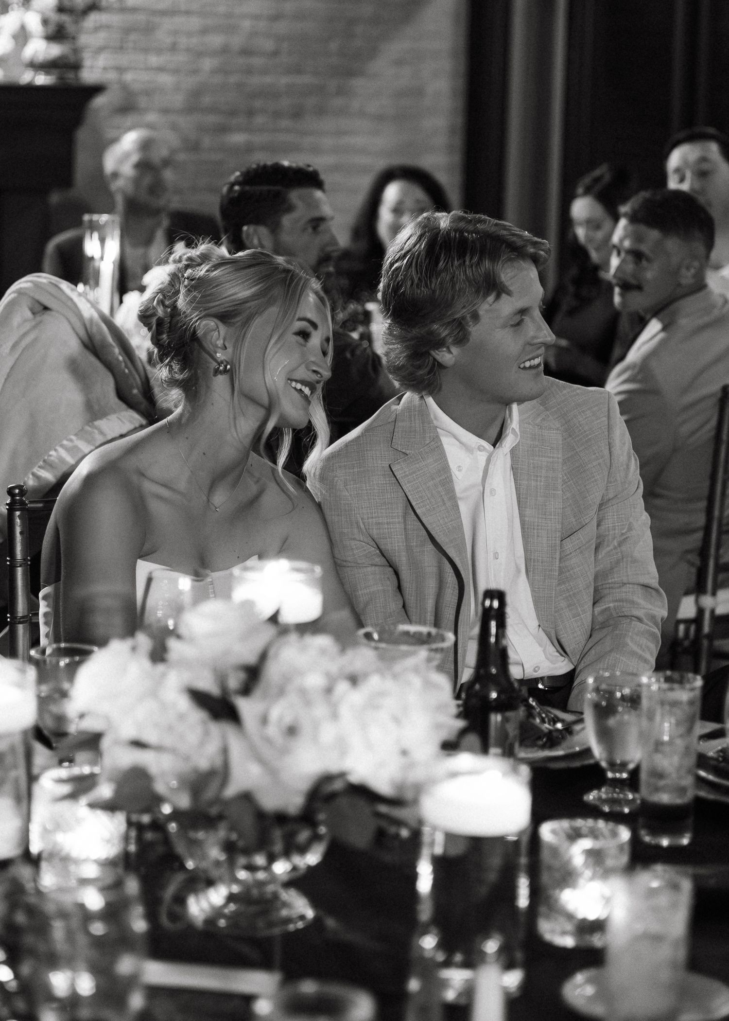 A black and white sequence showing a couple sharing candid moments at a dimly lit reception venue.