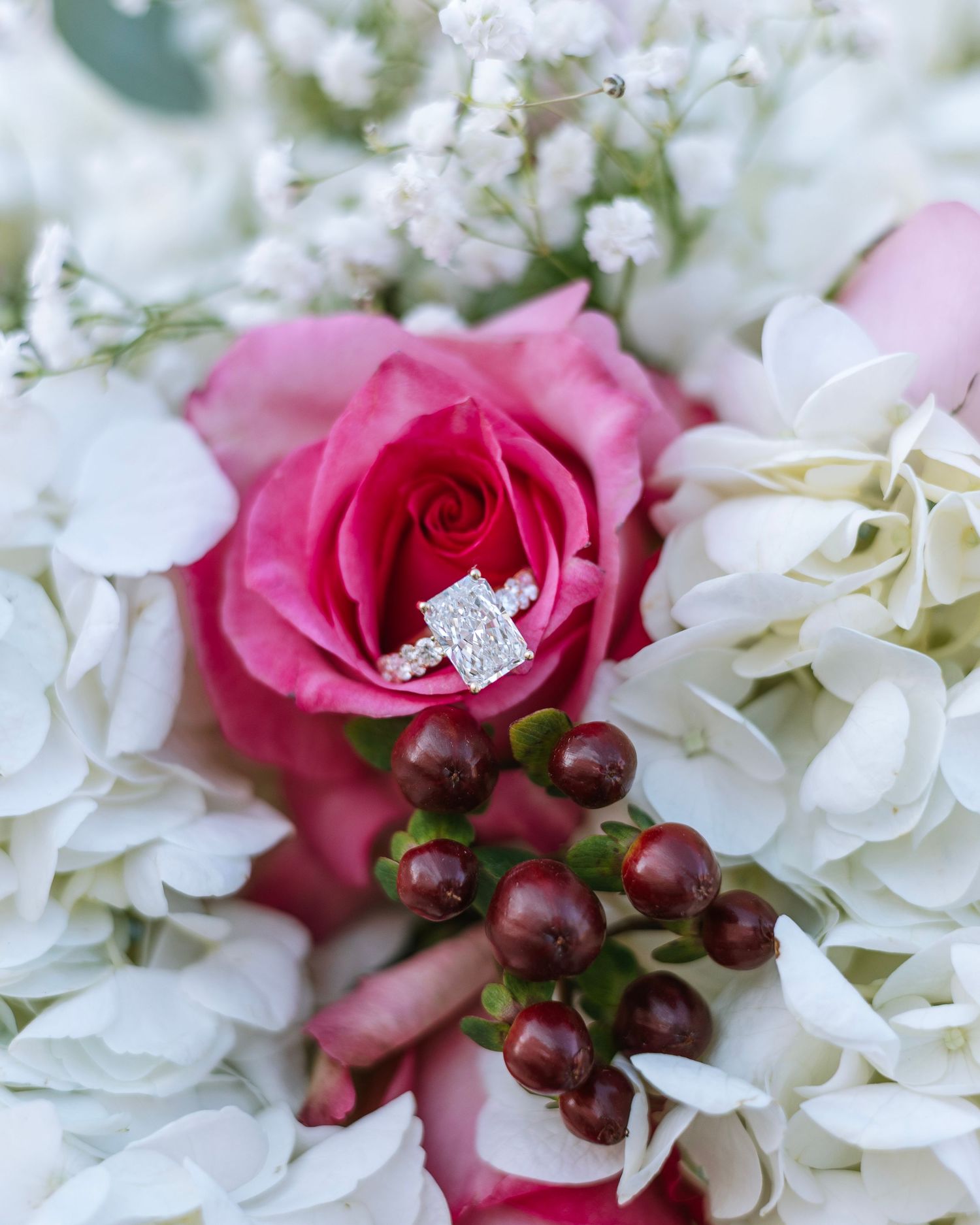 Close-up of pink roses and white hydrangeas with an engagement ring.