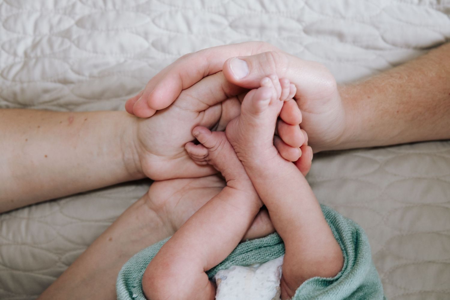 Close-up of tiny baby feet being gently held by caring hands.