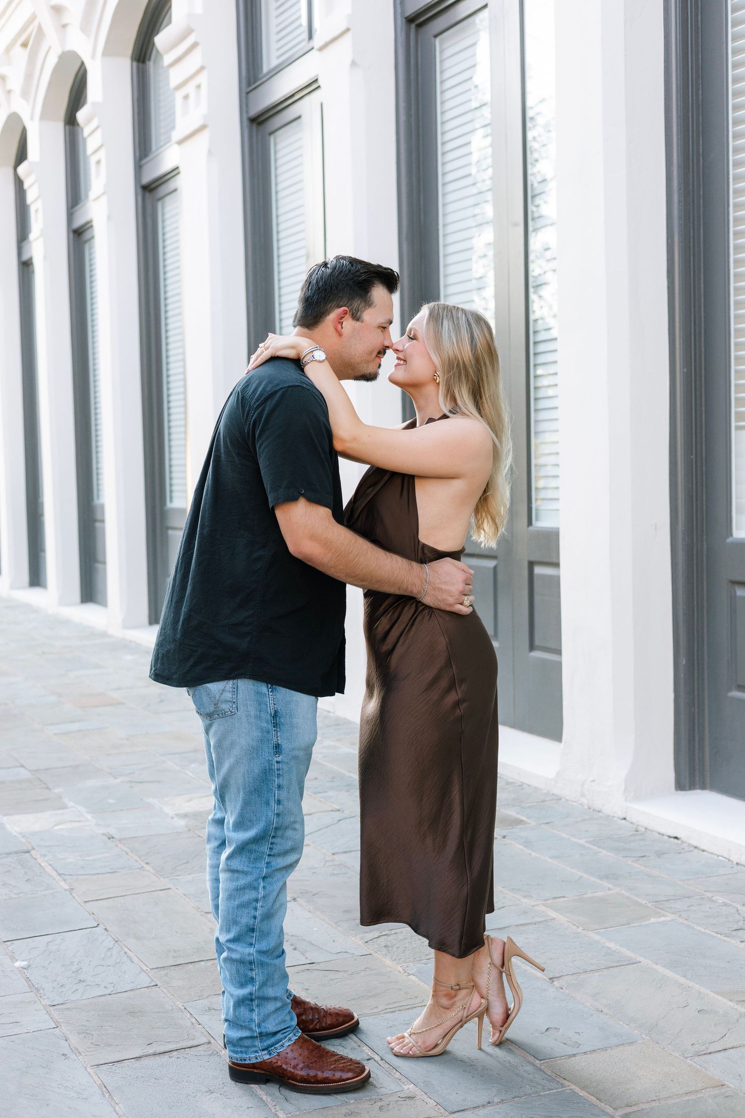 Romantic couple embracing in front of a white columned building.