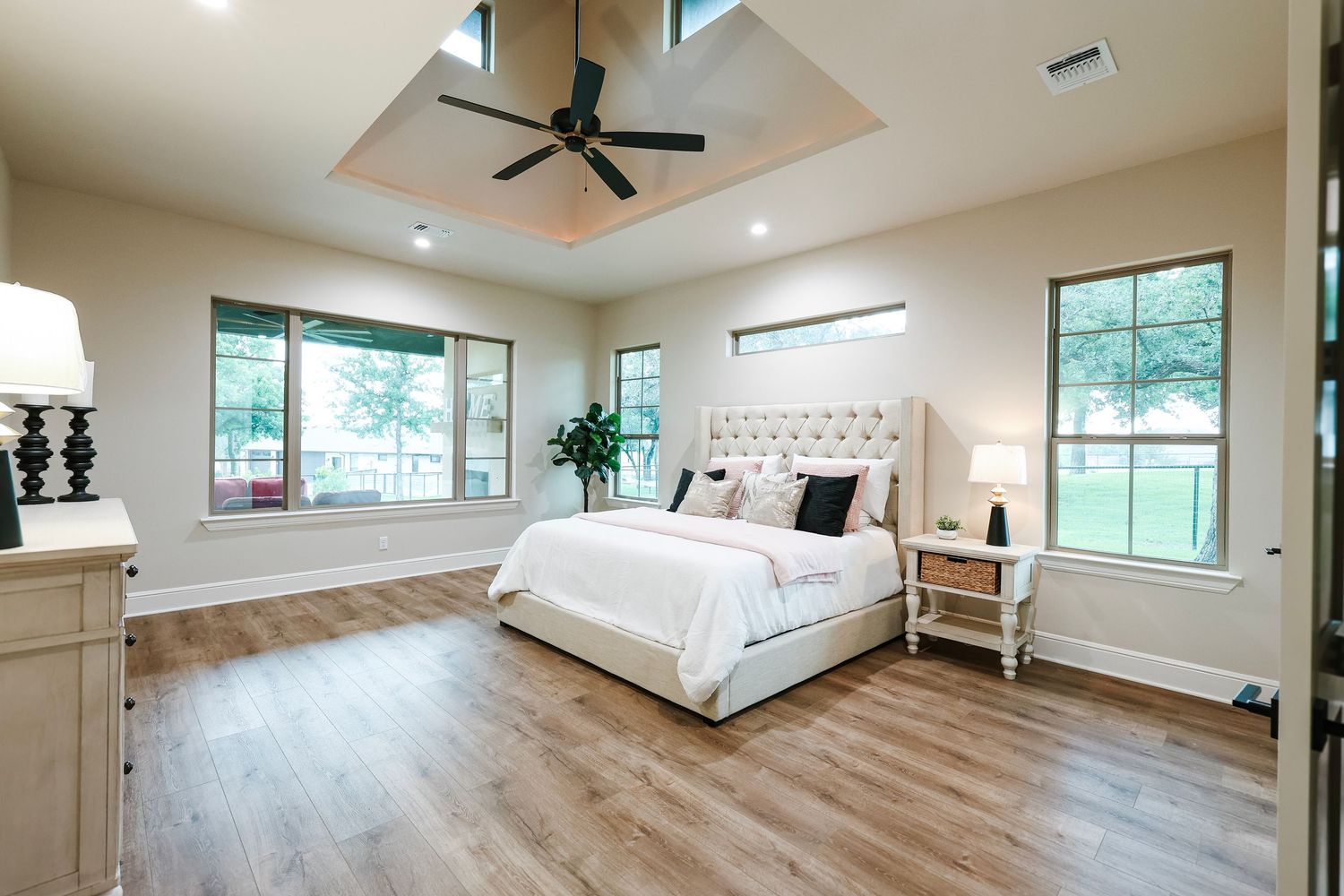 Spacious master bedroom with large windows, ceiling fan, and hardwood floors.