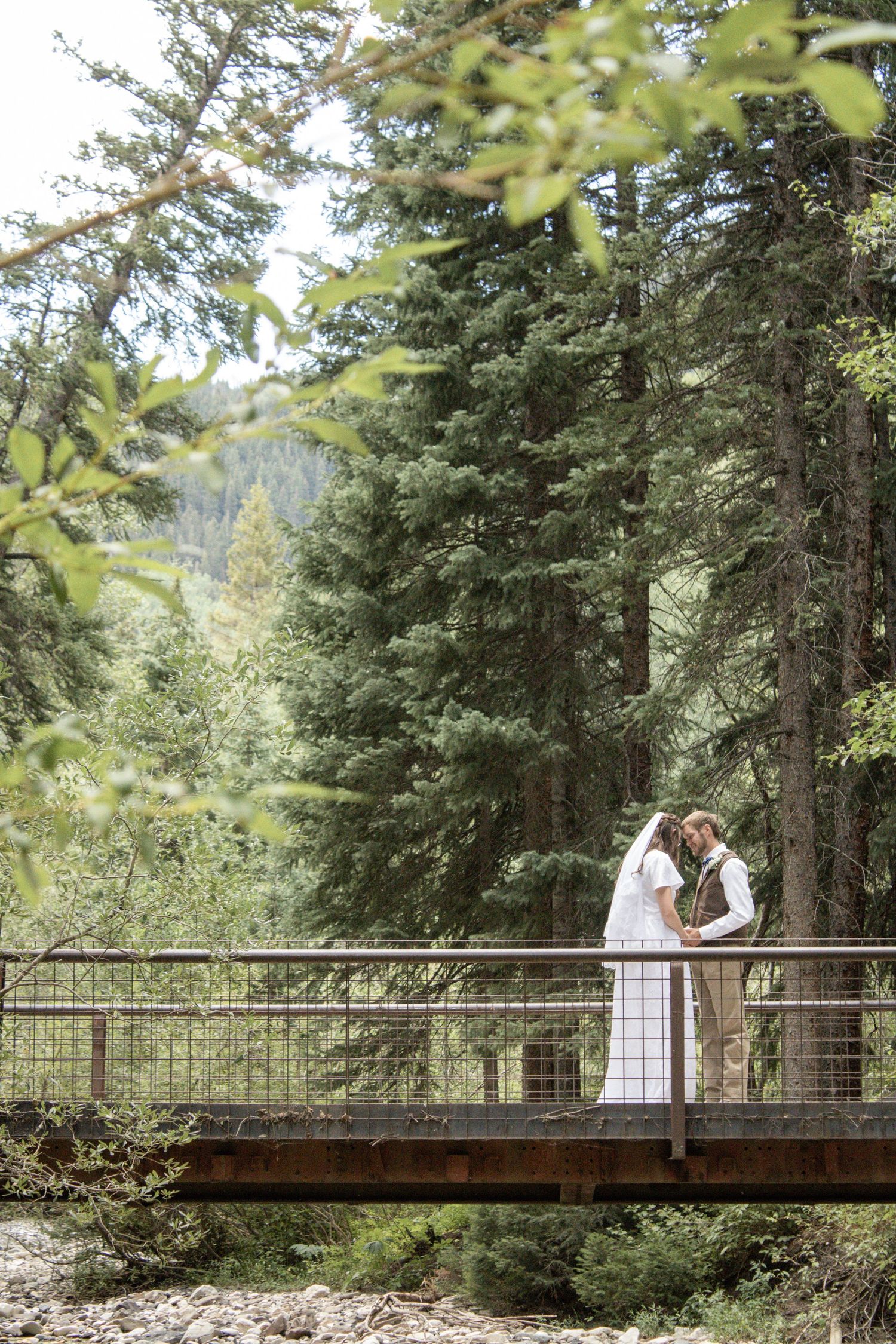 bride and groom pose on bridge