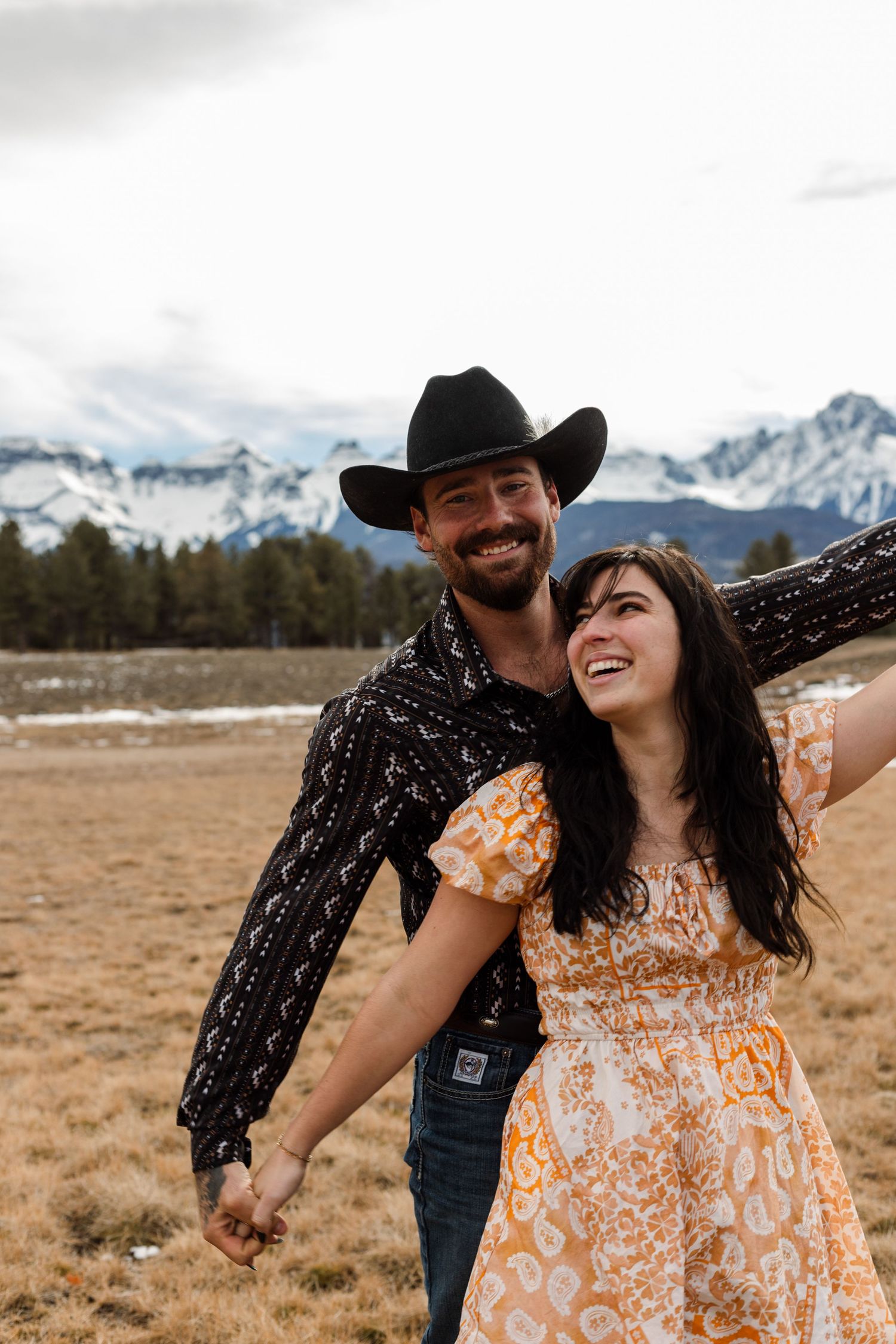 couple laughs in front of mountain background