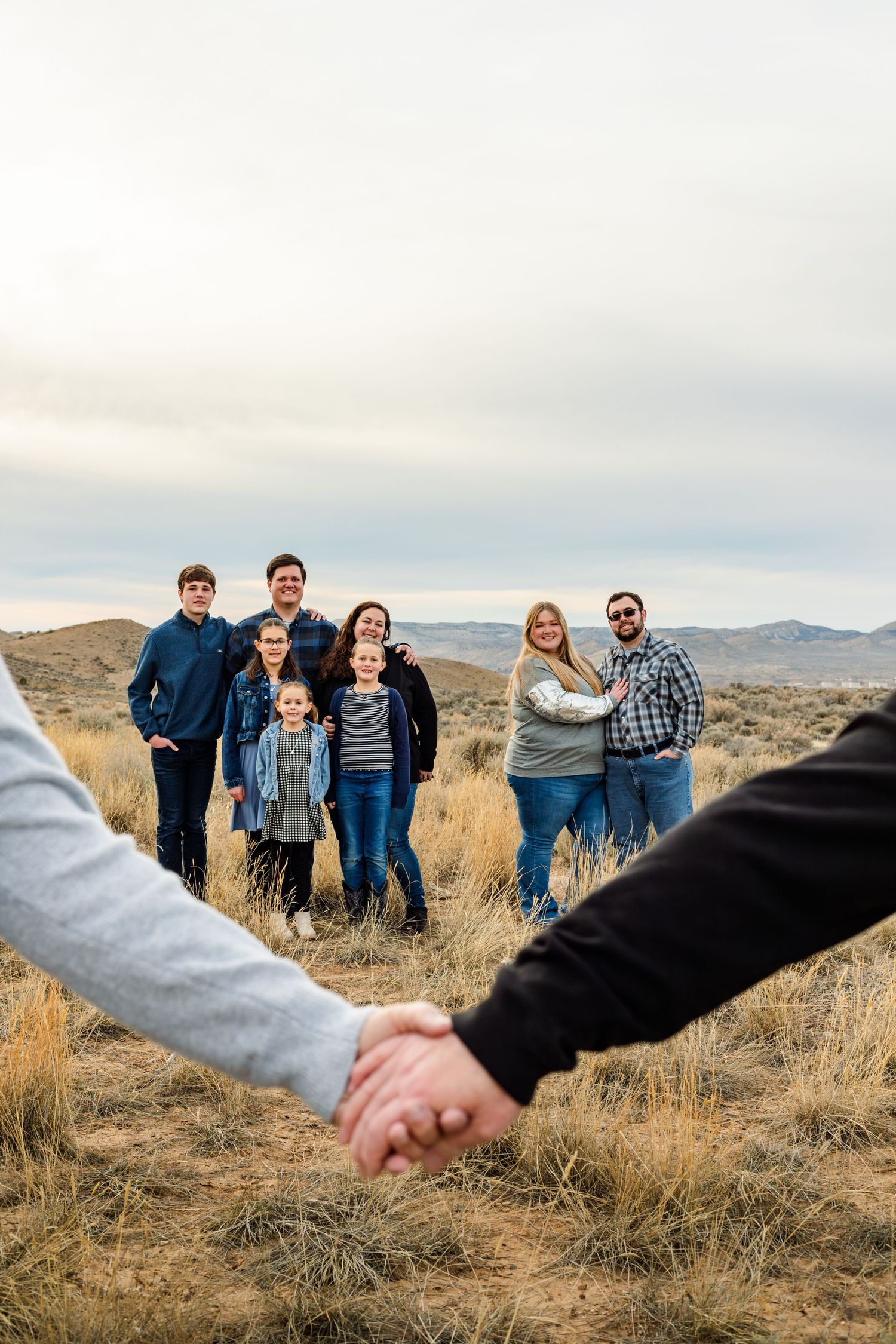 grandparents hold hands in the foreground with family in the background