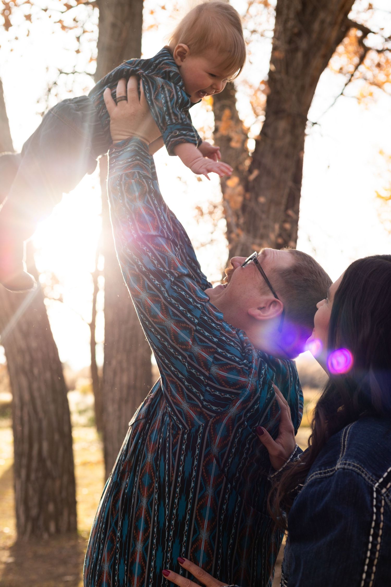 dad lifts baby into the air as mom watches