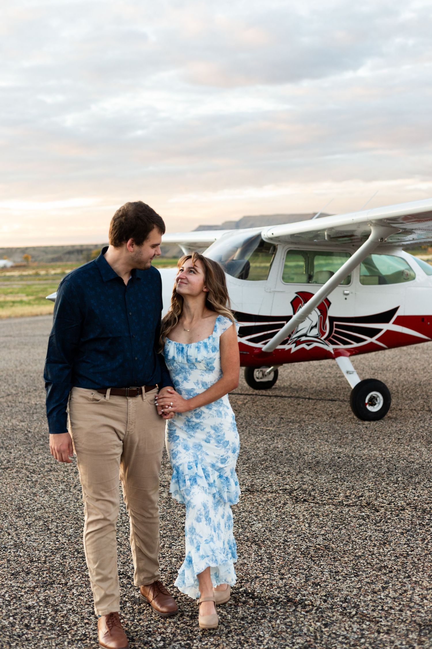 couple walks together in front of small airplane