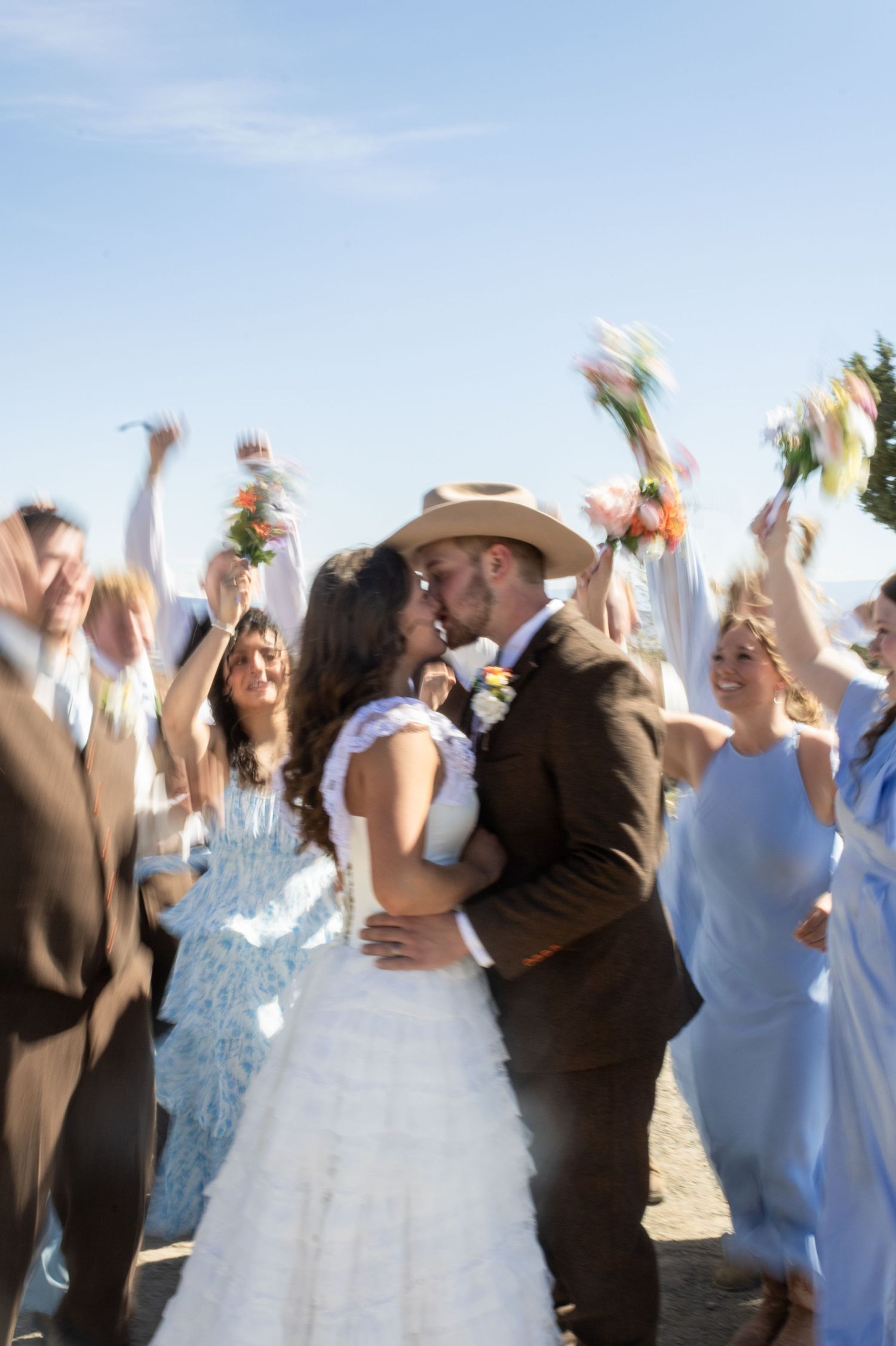 Bridal party cheer a bride and groom kiss