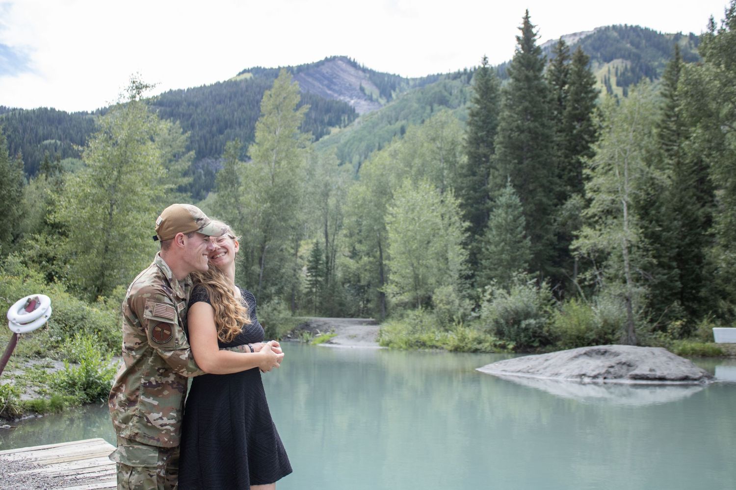 Couple poses together in front of pond.