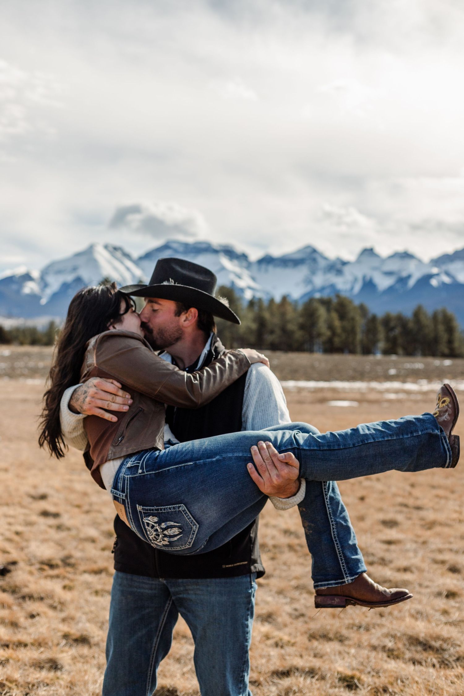 couple kisses in front of mountain background