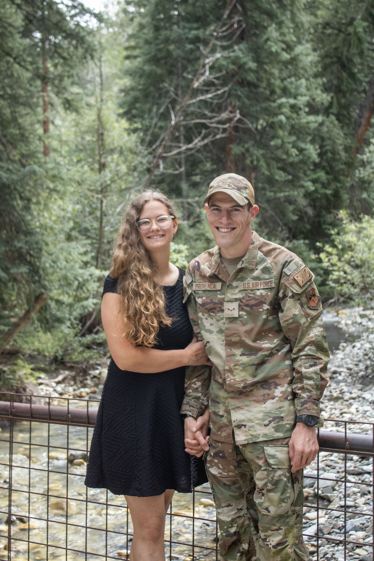 Couple poses together in front of river.