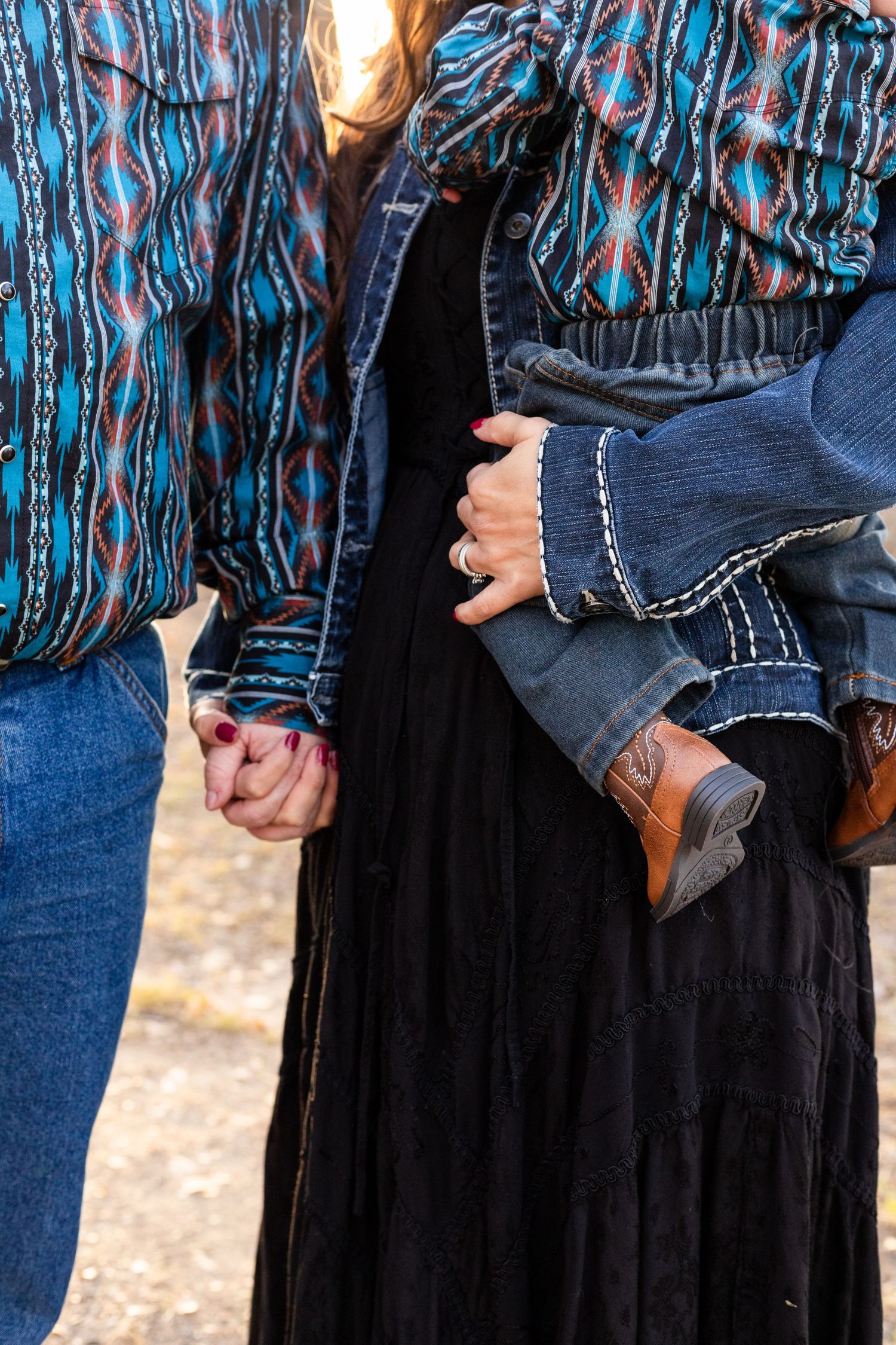 mom and dad hold hands while mom holds baby