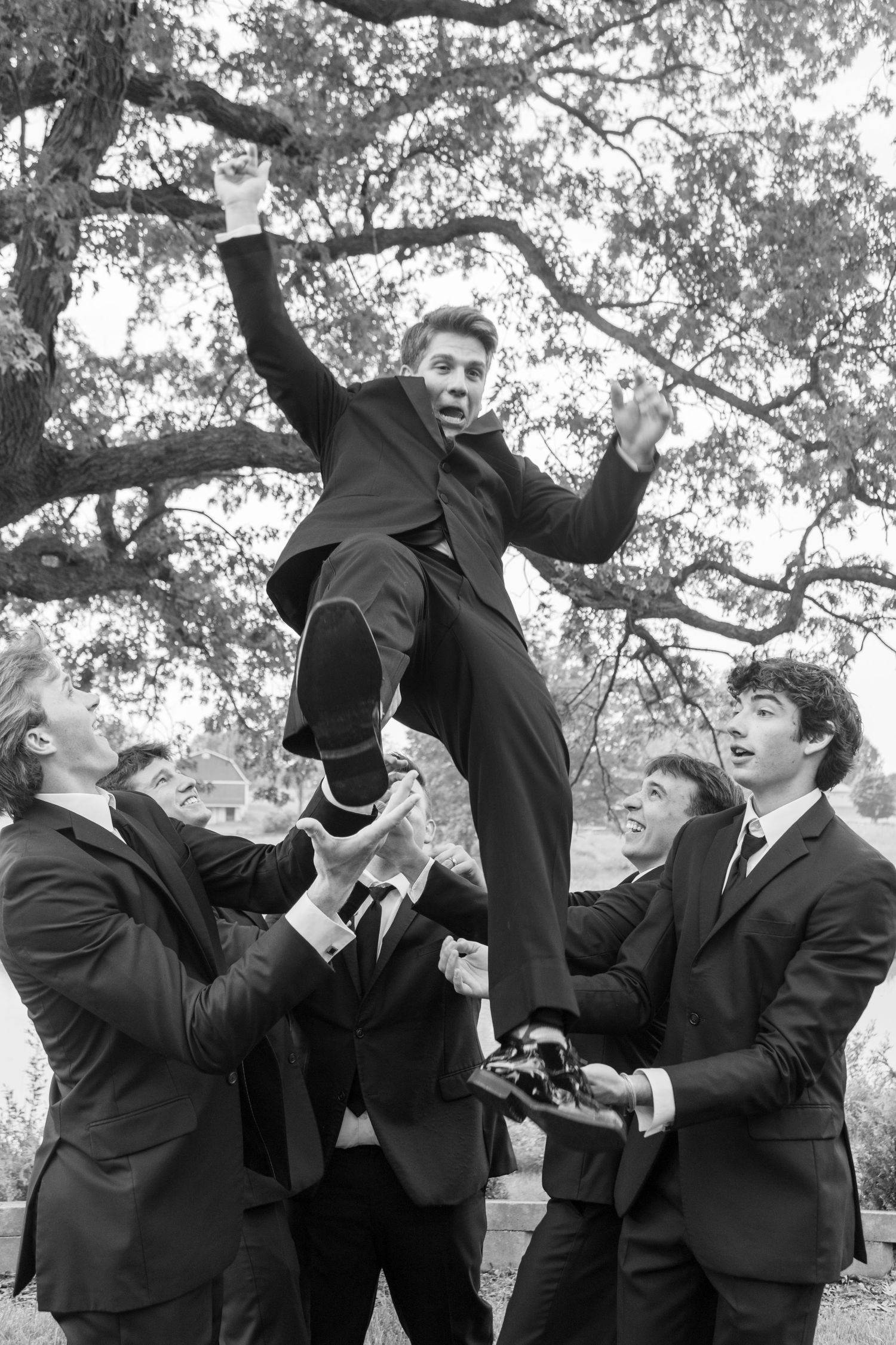 groomsmen throw groom into the air