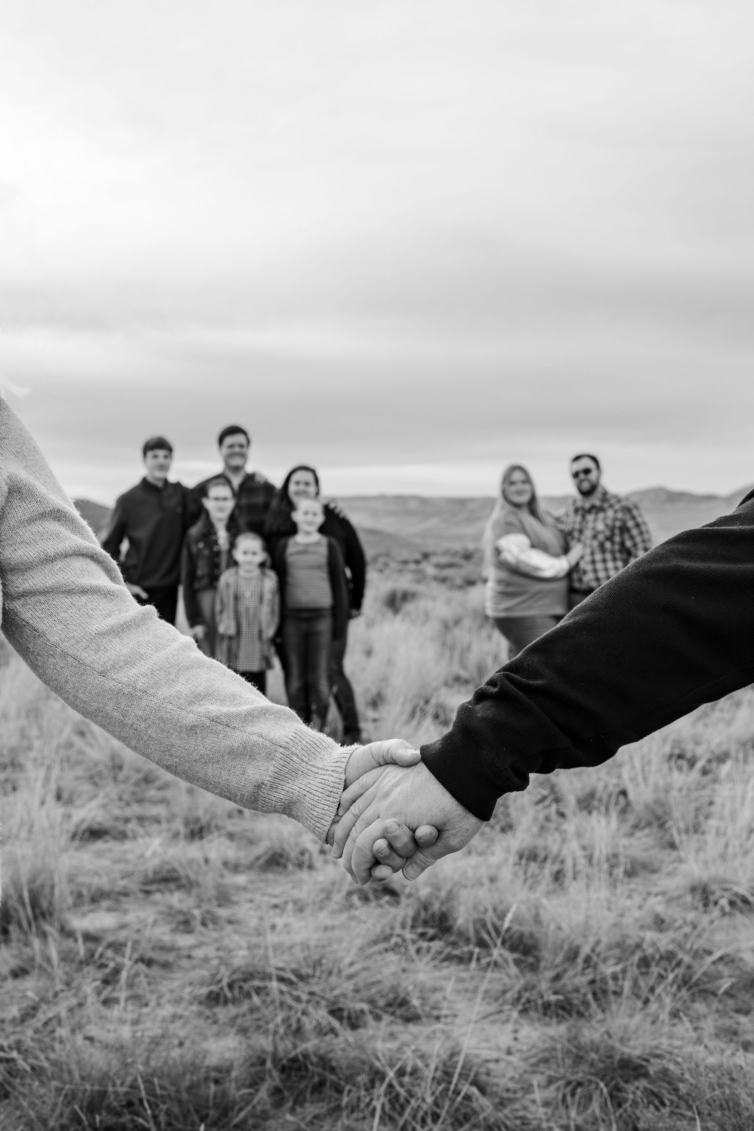 grandparents hold hands in the foreground with family in the background