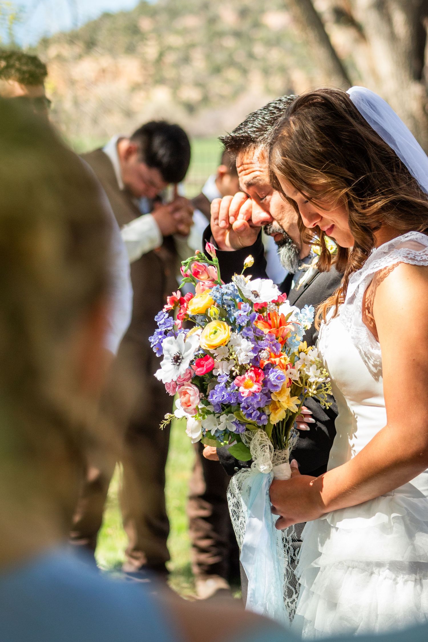 Bride stands with father at the front of the isle as he wipes away tears.