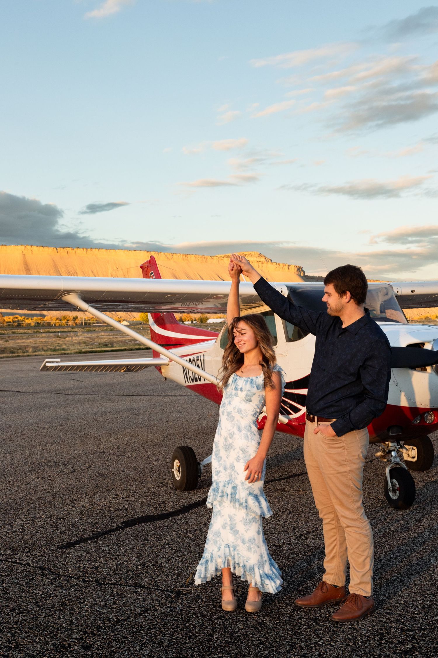 man spins fiance in front of small airplane