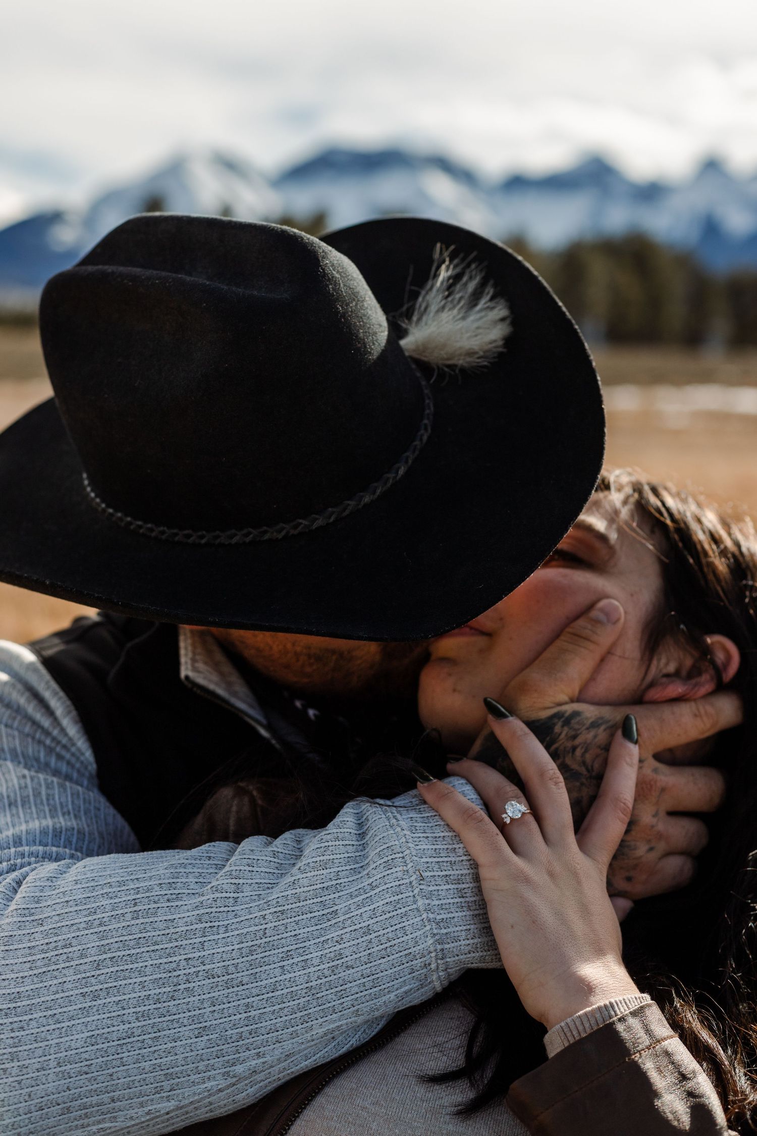 couple kisses in front of mountain background