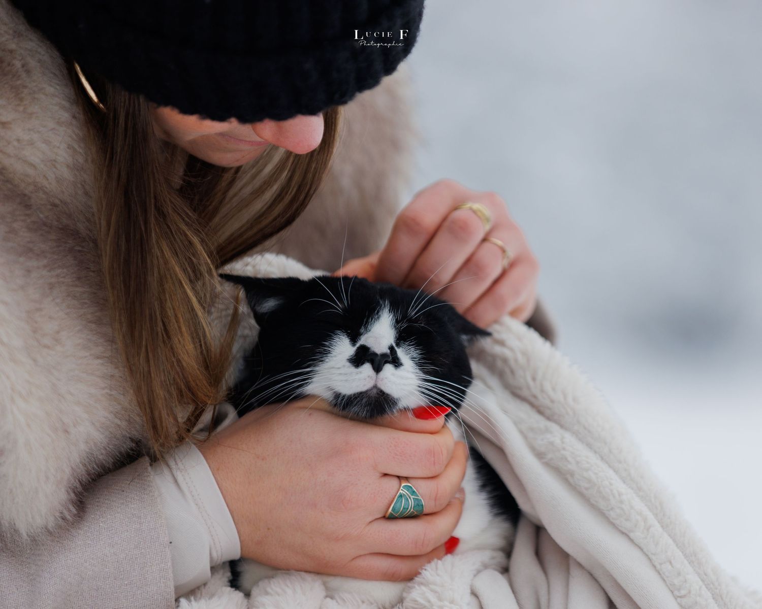 A black and white tuxedo cat rests comfortably in someone's lap while being petted.