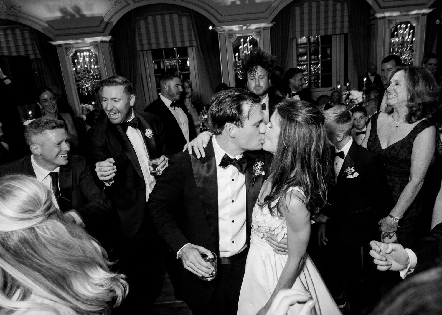 Bride and groom share a kiss on the dance floor surrounded by guests at an elegant wedding reception at St Regis Hotel in NYC.