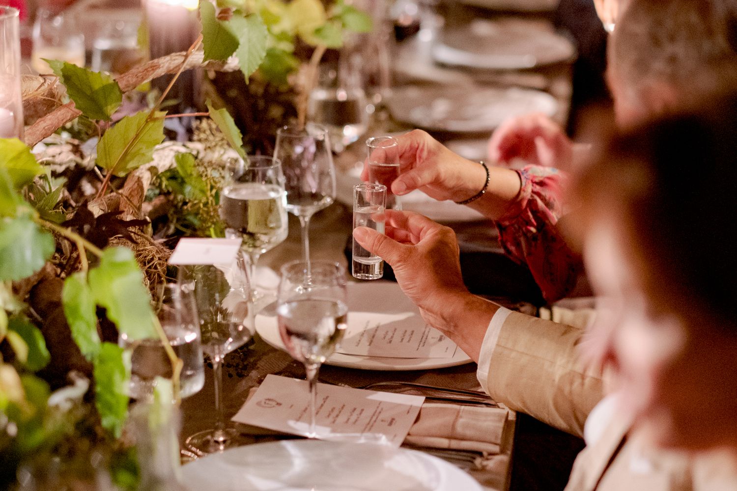 Elegant dinner table setting with wine glasses, table decor and greenery at a formal dining event.