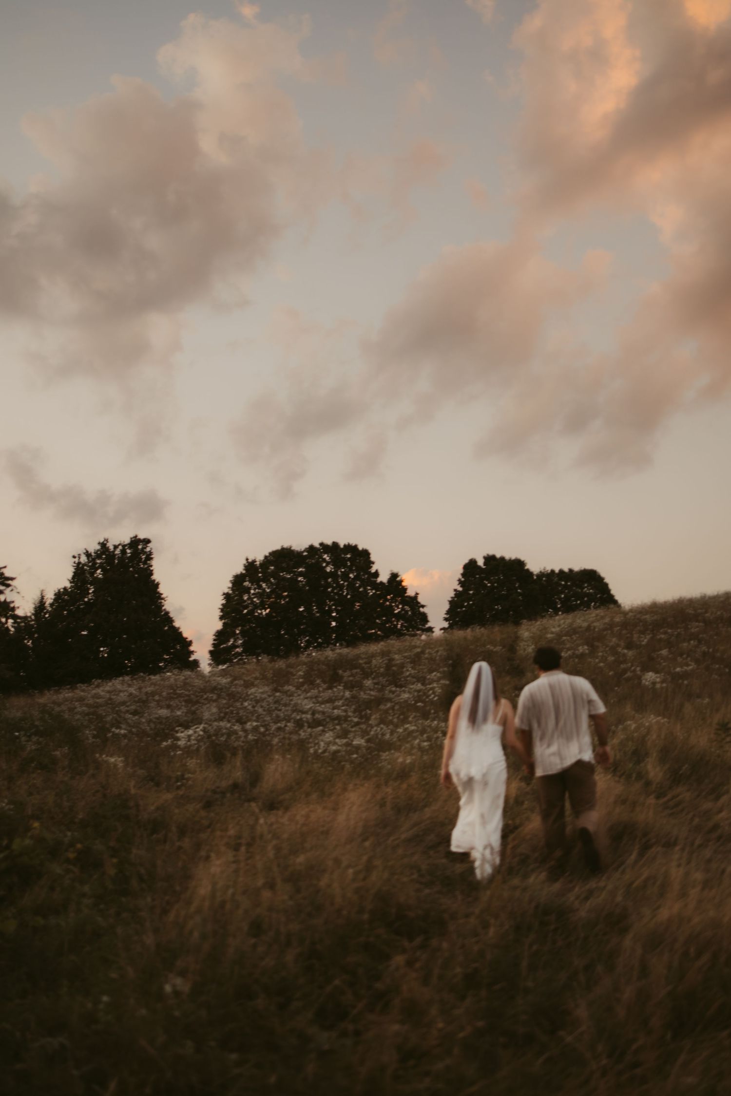 Two figures walk along a hilltop silhouetted against a dramatic sunset sky.
