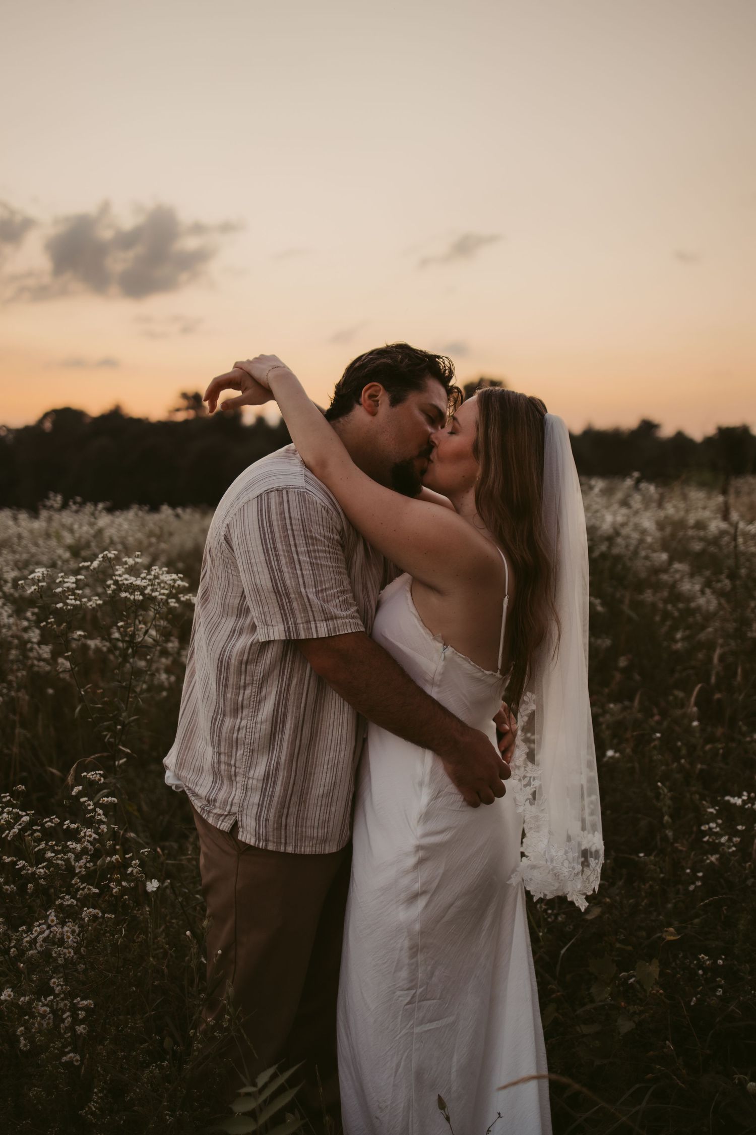 A romantic sunset photoshoot in a field of white wildflowers during golden hour.