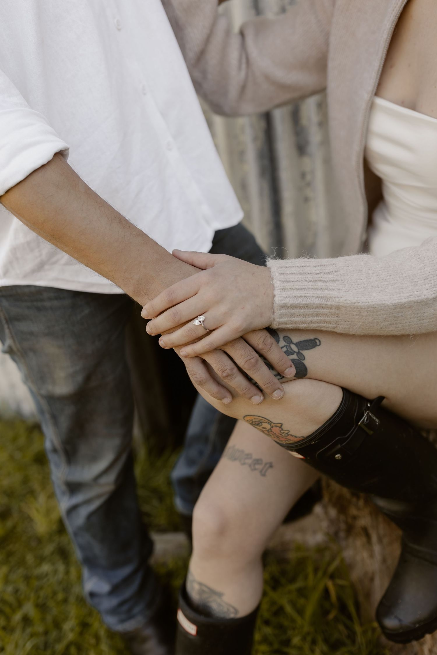 Detail shot of hands placing or adjusting a tattoo on skin against a light background.
