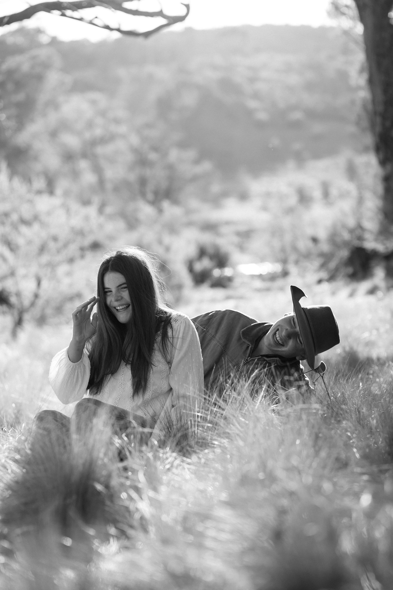 Black and white photo of a woman relaxing in tall grass during a sunny afternoon in nature.