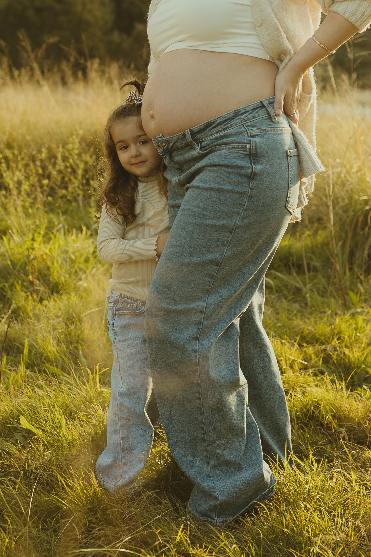 Family members share an intimate moment in a sun-drenched field.
