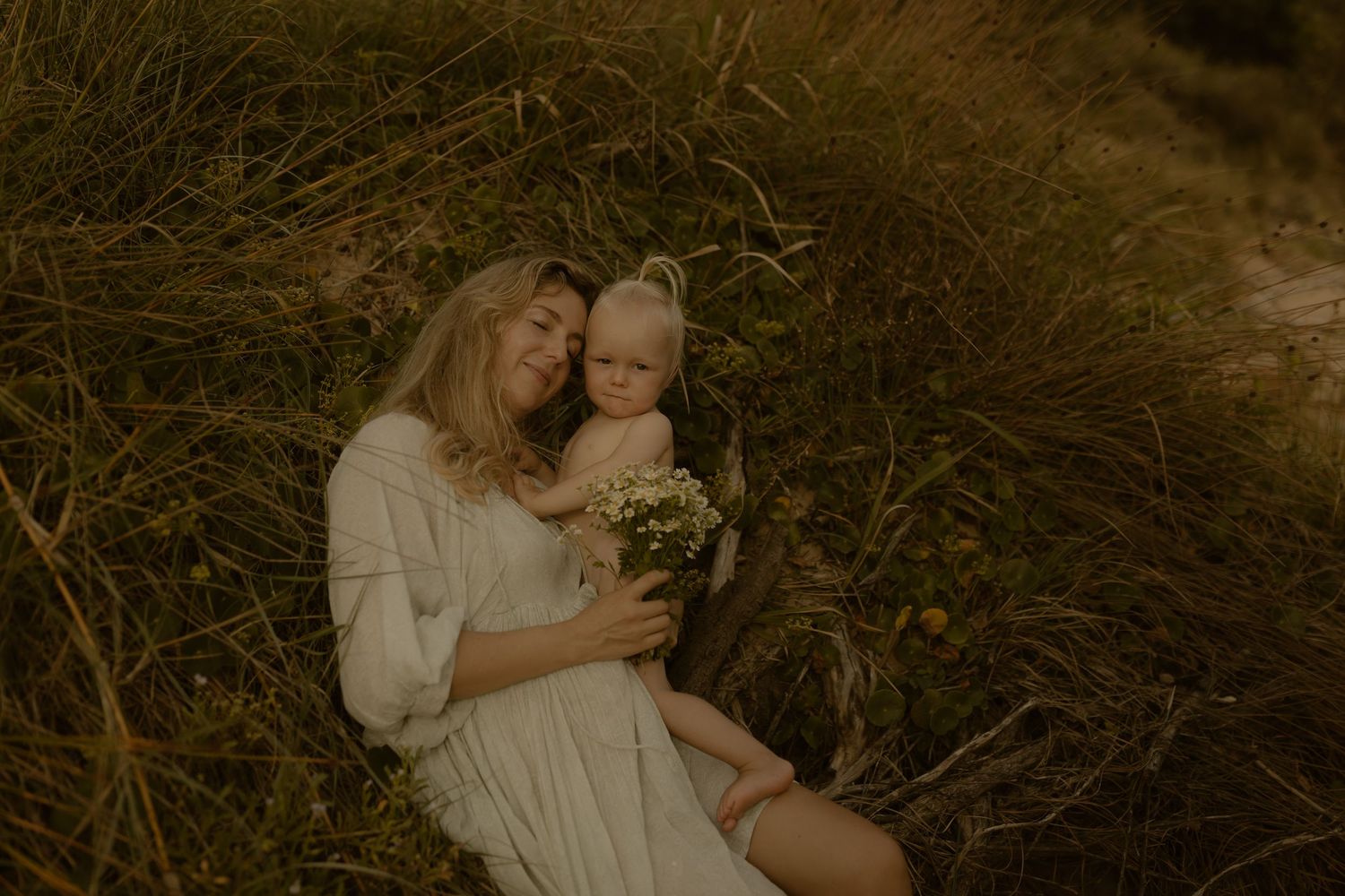 Intimate sepia-toned photograph capturing tender moments by a natural waterside setting.