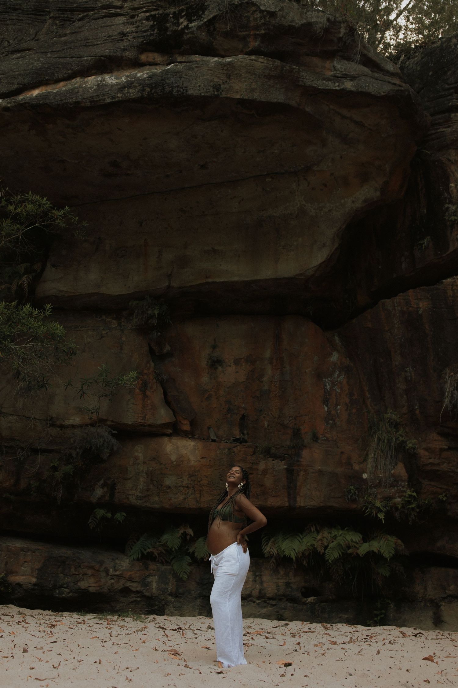 A series of photos showing someone in a white dress against dark rocky cliffs during a photoshoot session.