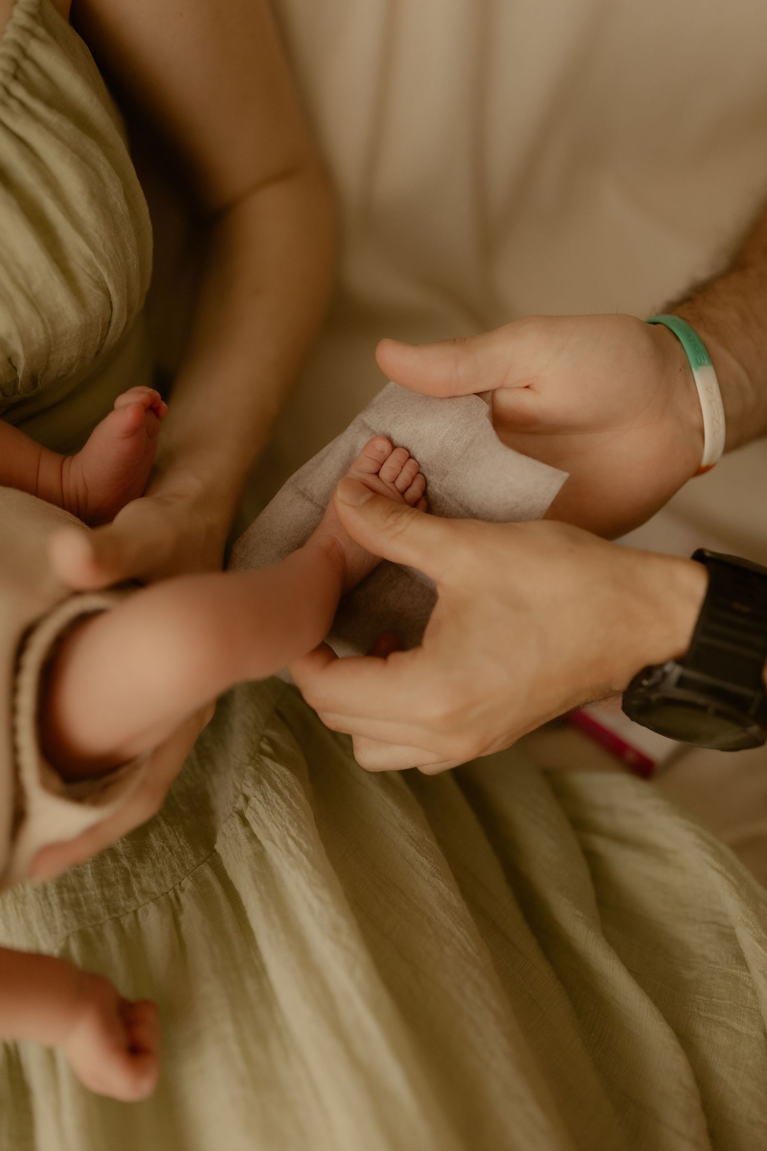 Multiple hands gently touching and holding tiny newborn fingers.